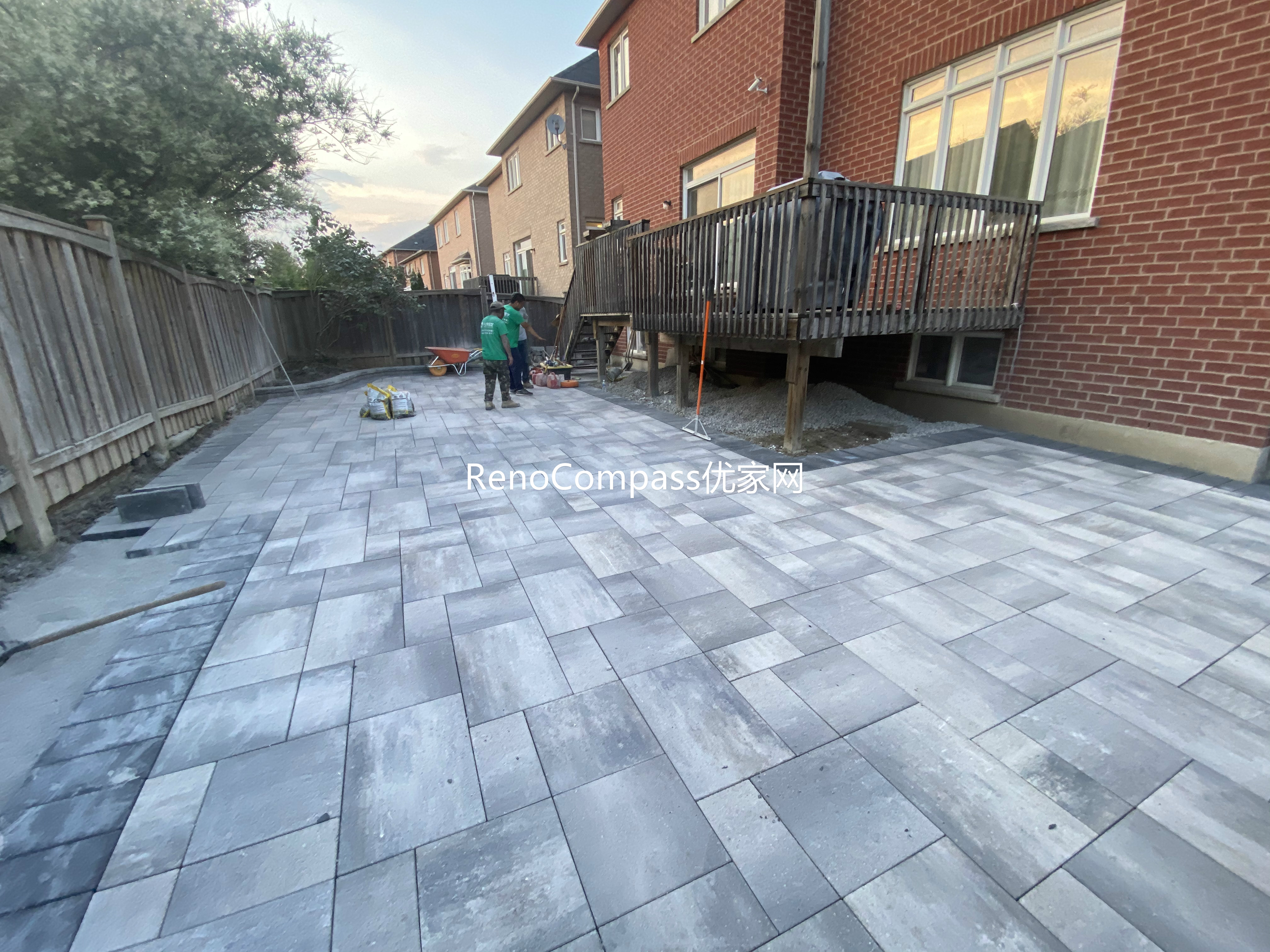 This Markham landscaping and interlocking project shows the installation phase of a large-format interlocking stone patio. The layout features precisely aligned pavers designed to create a durable, level surface that enhances both functionality and visual consistency across the backyard. The patio extends from the home toward the rear fence, providing a spacious outdoor area suitable for gatherings and everyday use. Careful base preparation and spacing ensure long-term stability and proper drainage, while the neutral stone tones complement the existing deck and brick exterior. This interlocking patio installation was completed by Reno Compass, serving homeowners in Markham and across the GTA.