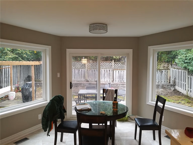 This Newmarket interior renovation features a bright breakfast nook enhanced by large bay windows and direct access to the backyard patio. Natural light, clean wall finishes, and updated flooring create a warm and functional dining space, showcasing the thoughtful layout and craftsmanship of a professional Toronto renovation company.