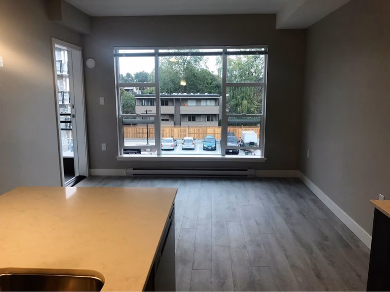 This Oakville condo renovation highlights a bright open living area featuring wide plank flooring, neutral wall tones, and a large window that brings in abundant natural light. The open-concept layout seamlessly connects the living and kitchen space, creating a clean, modern, and functional environment ideal for comfortable condo living in Oakville.