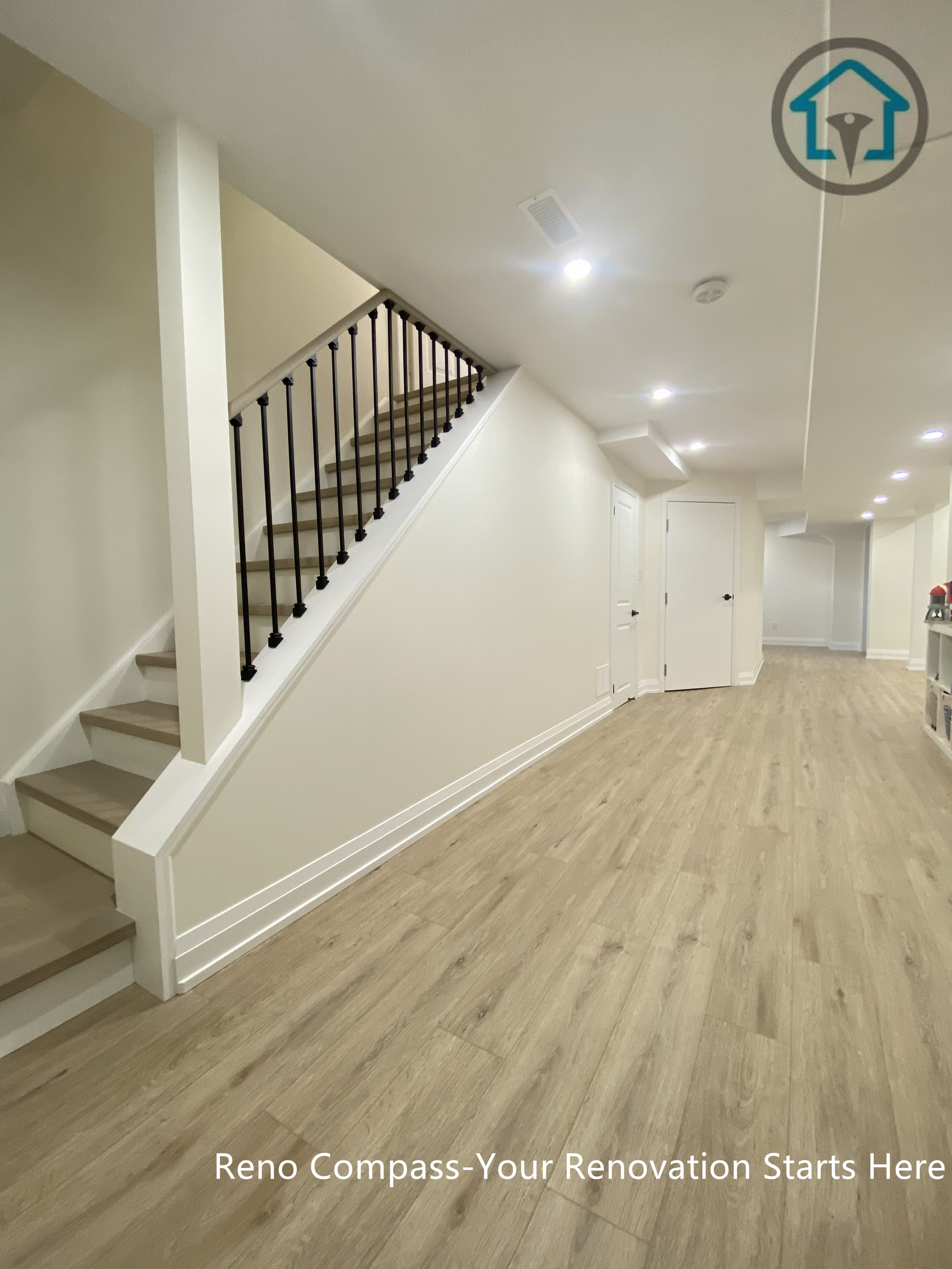 Modern flooring and staircase renovation in Markham featuring light oak hardwood floors, white riser stairs, and black iron balusters. The open staircase design enhances natural light flow and creates a clean, contemporary interior transition between floors. Completed by a professional Toronto renovation company with a focus on durability, safety, and timeless aesthetics.