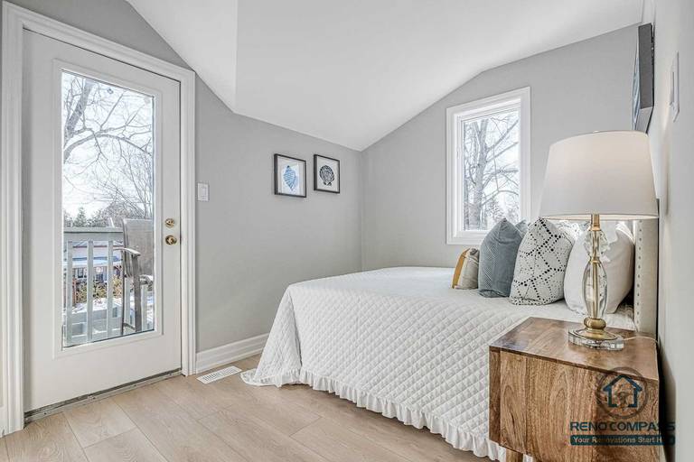 This Georgian interior renovation features a bright bedroom with a balcony door, clean wall finishes, and light wood flooring. Soft tones and natural light create a calm, comfortable private space completed by a Toronto renovation company.