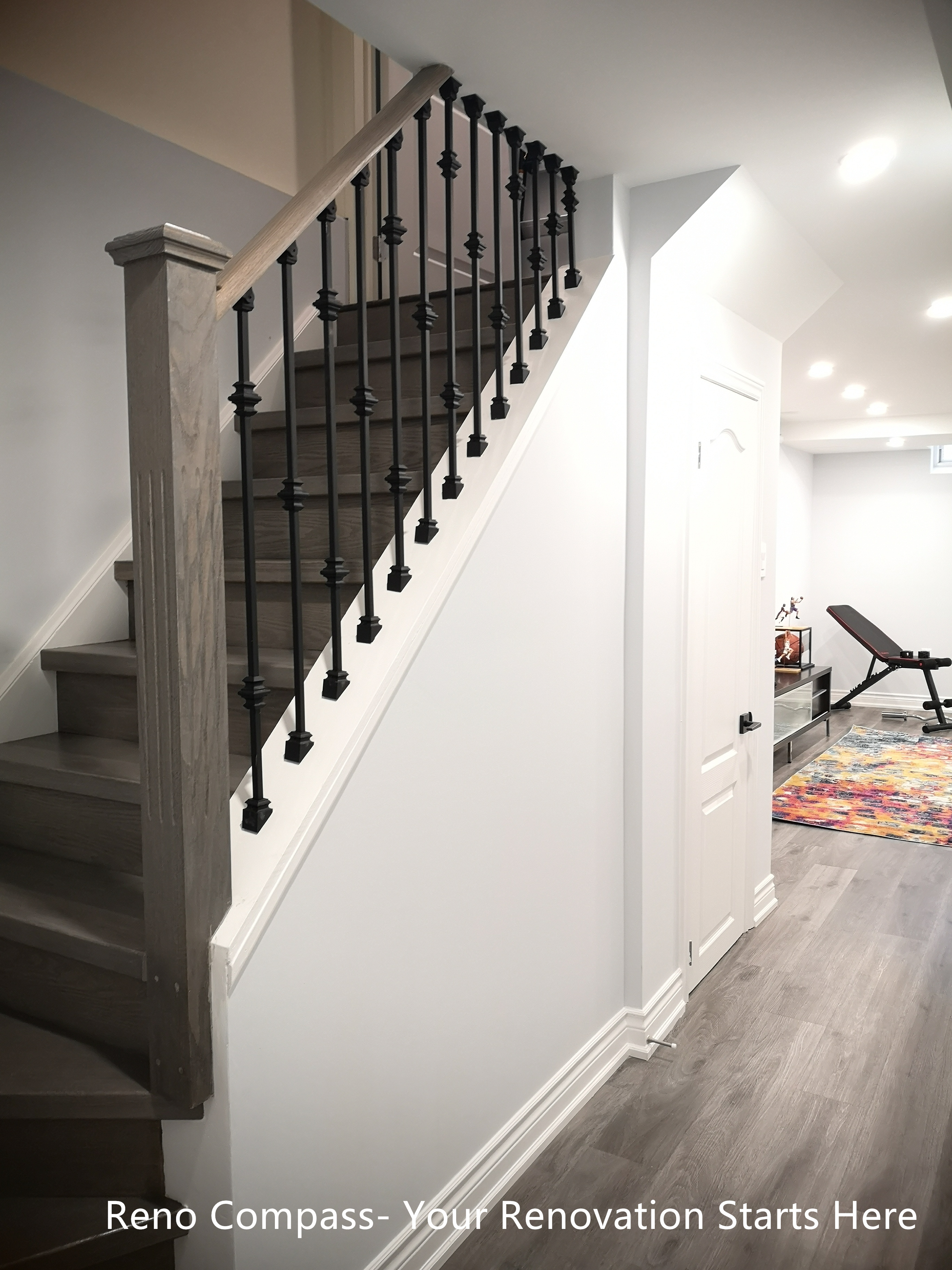 This Whitby basement renovation features a newly upgraded staircase designed to improve safety, durability, and visual continuity. The staircase combines wood-look treads with black metal balusters, creating a clean contrast that complements the modern basement flooring. White stringers and walls enhance brightness while maintaining a streamlined appearance. The staircase connects seamlessly with the finished basement space, supporting smooth circulation and a cohesive overall design suitable for long-term residential use.