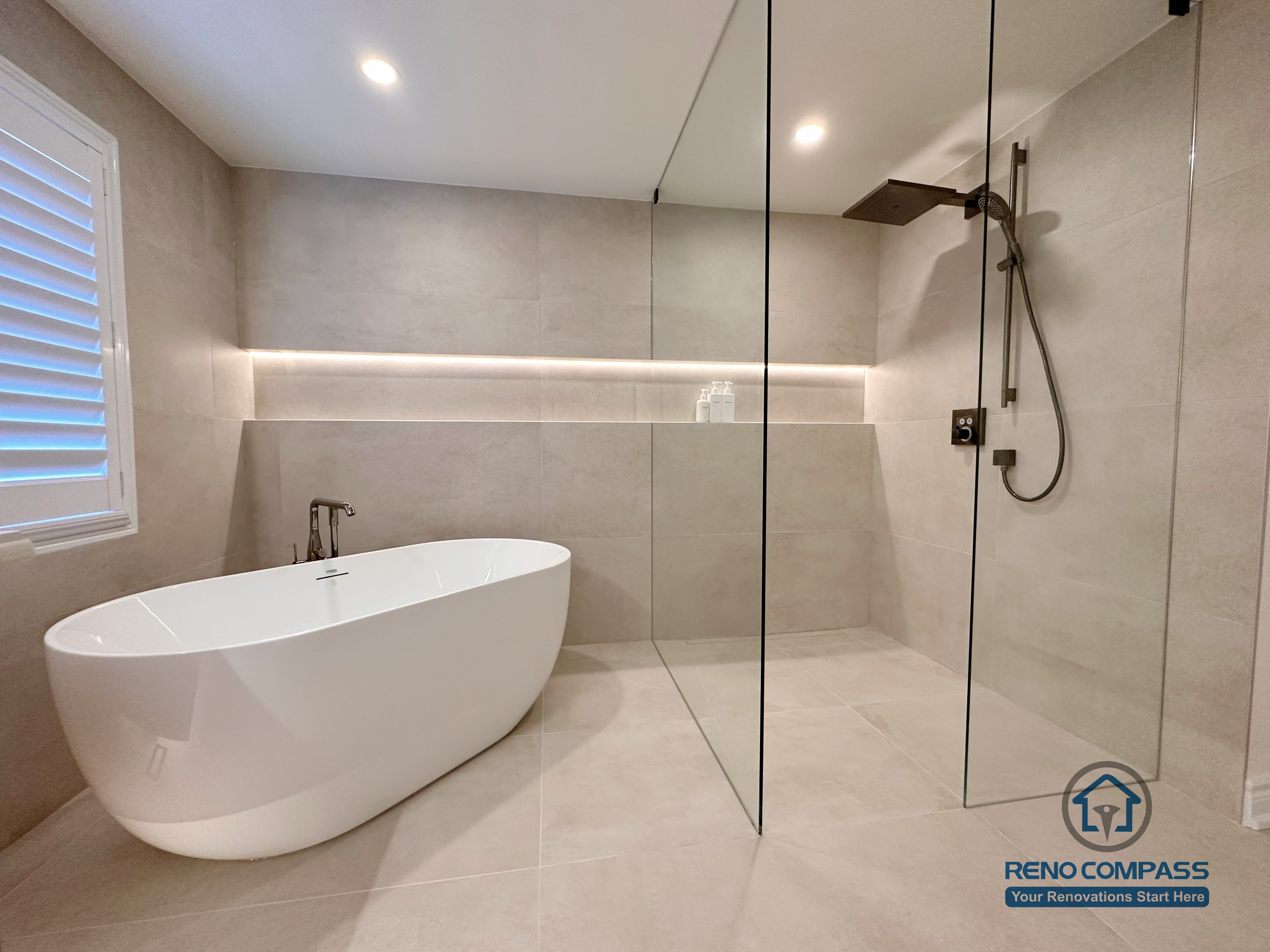 This Markham accessible bathroom renovation features a freestanding bathtub positioned within a barrier-free layout, allowing easy movement and step-free access. Large-format floor and wall tiles, integrated linear lighting, and a custom wood-tone vanity contribute to a calm, safe, and modern environment. Designed and built by a professional Toronto renovation company, Reno Compass Inc., the space prioritizes accessibility, comfort, and long-term usability.