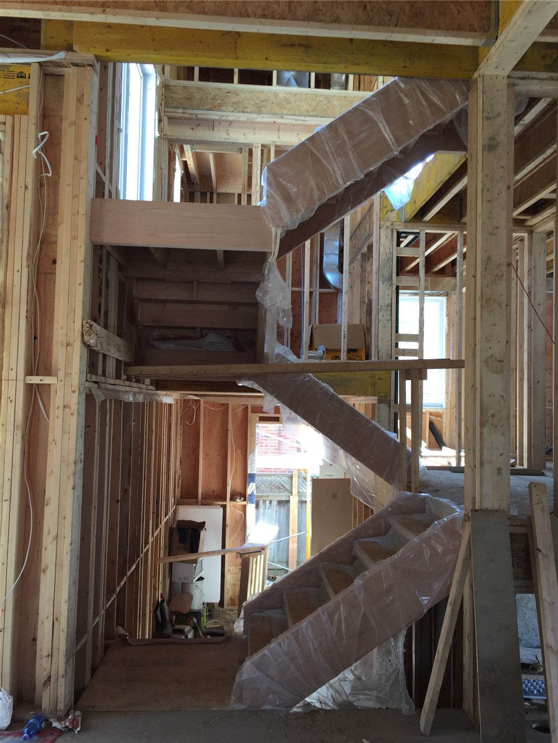 This image shows a multi-level staircase installation during a residential renovation project in Toronto. The custom wood staircase structure is carefully positioned within the framed interior, connecting different floors while ensuring proper support and alignment. Protective wrapping helps preserve the stair components during construction. As a trusted Toronto Renovation Company, Reno Compass Inc. specializes in custom staircase installation and structural renovation, delivering durable and well-crafted stair systems for homes across Toronto and the Greater Toronto Area.