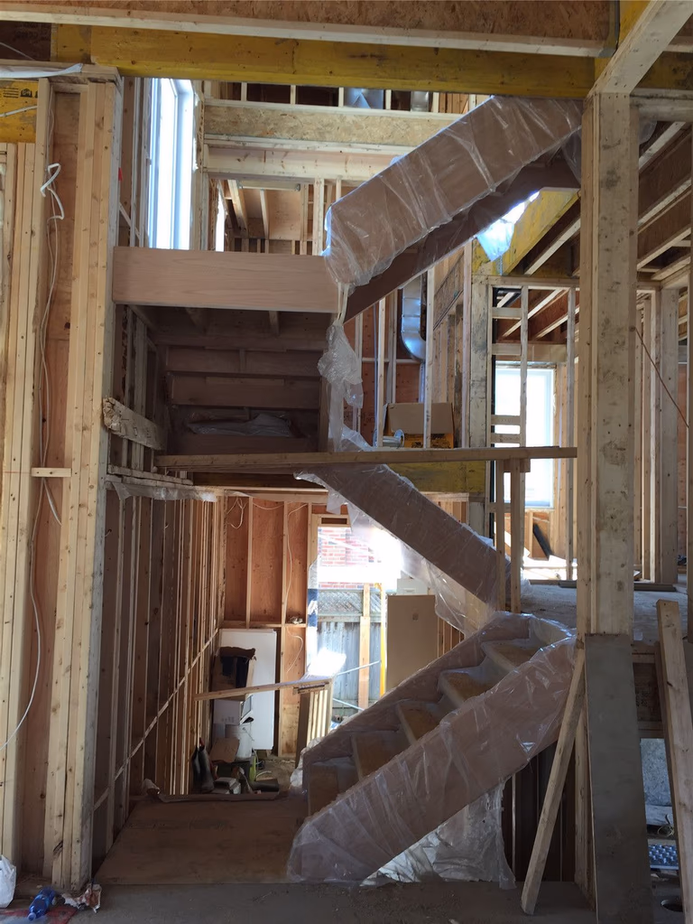 This image shows a multi-level staircase installation during a residential renovation project in Toronto. The custom wood staircase structure is carefully positioned within the framed interior, connecting different floors while ensuring proper support and alignment. Protective wrapping helps preserve the stair components during construction. As a trusted Toronto Renovation Company, Reno Compass Inc. specializes in custom staircase installation and structural renovation, delivering durable and well-crafted stair systems for homes across Toronto and the Greater Toronto Area.