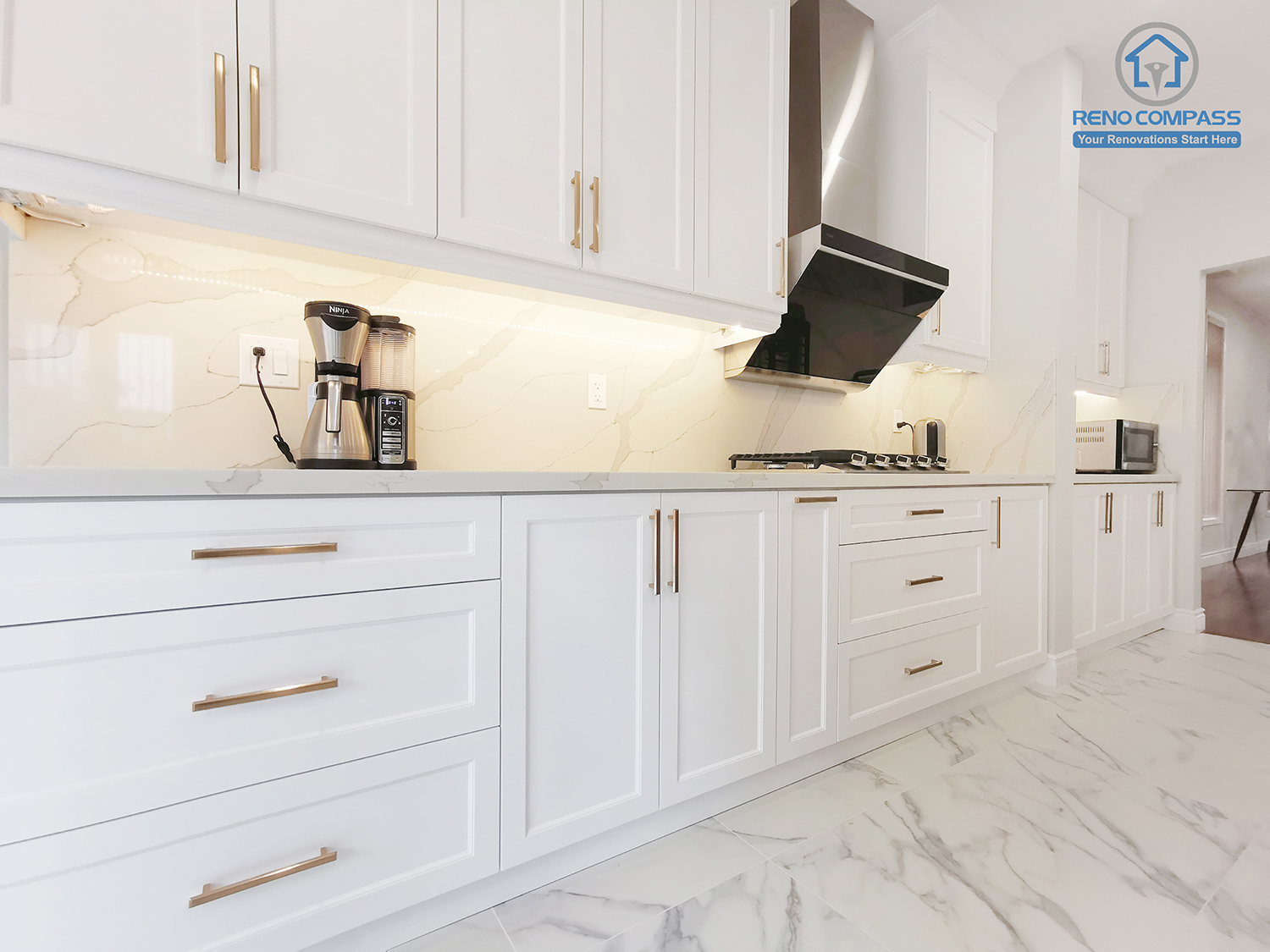 This Markham interior renovation highlights the detailed craftsmanship of custom kitchen cabinetry designed for both functionality and visual consistency. Full-height white shaker cabinets provide generous storage while maintaining clean, proportional lines across the elevation. Quartz countertops and a continuous stone-look backsplash enhance durability and ease of maintenance, creating a seamless work surface. Integrated lighting beneath the cabinetry improves task visibility and adds warmth to the overall space. Completed by Reno Compass, this kitchen renovation reflects a balanced approach to material selection, storage planning, and long-term usability tailored for contemporary Markham homes.