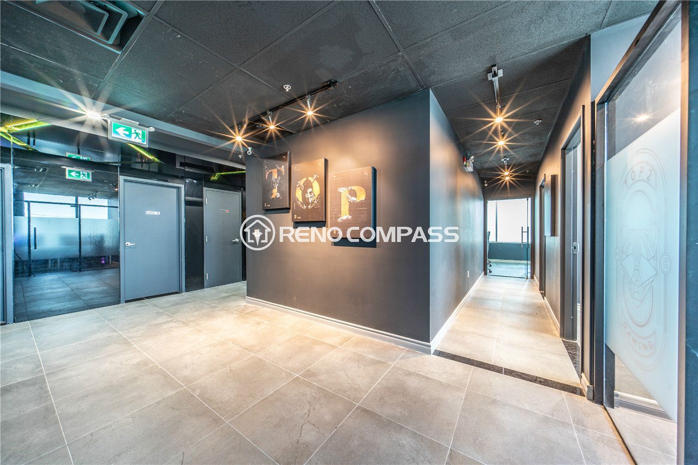 Modern internet cafe and gaming lounge renovation in Markham featuring open hallway layout, industrial black ceiling design, decorative wall art, glass doors, and durable commercial tile flooring. This commercial renovation project highlights professional lighting installation, clean partition construction, and contemporary interior finishing to create a stylish and functional gaming environment by experienced Toronto renovation contractor Reno Compass Inc.