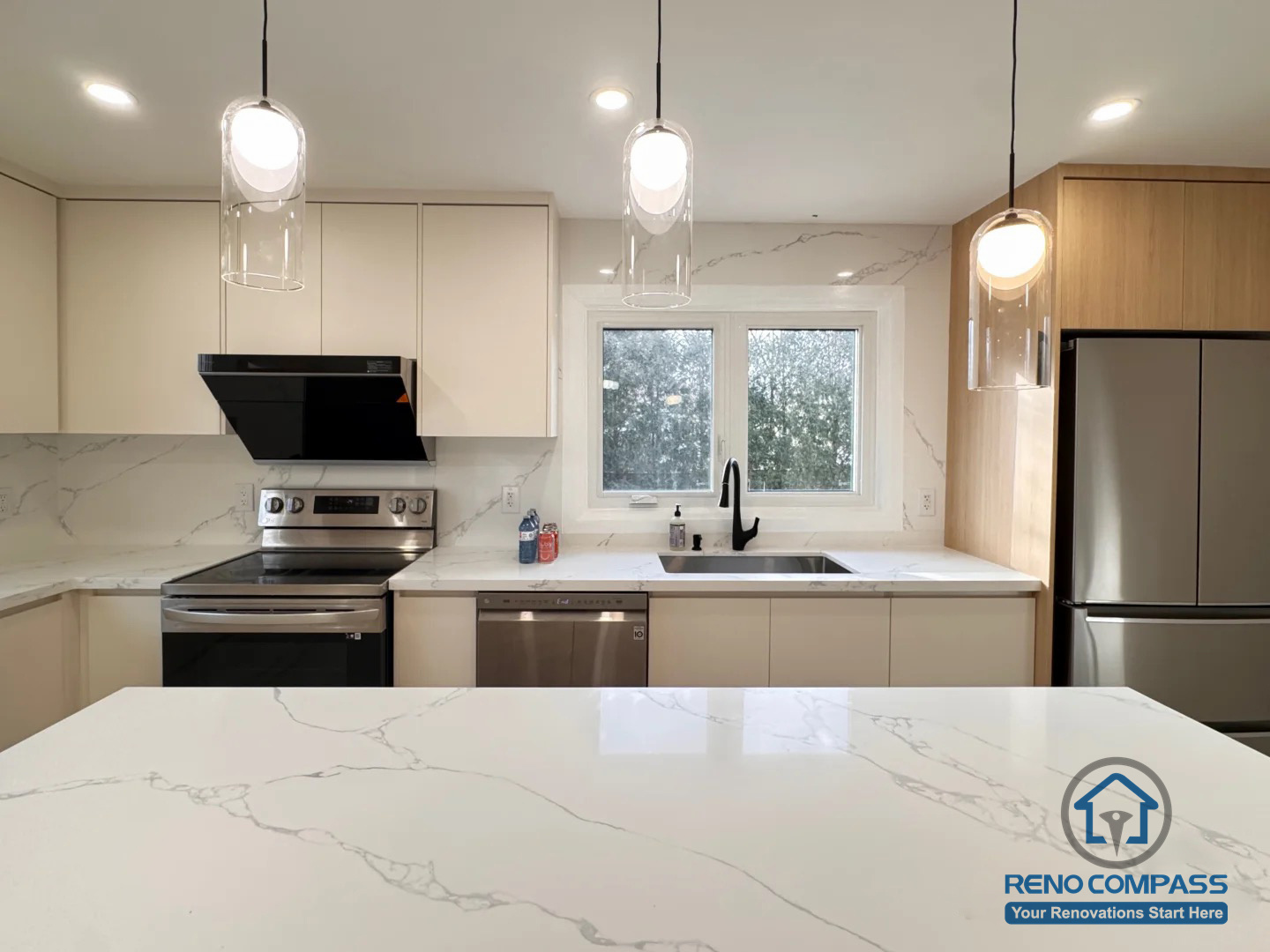 This Oakville kitchen renovation highlights a streamlined layout with full-height cabinetry, quartz countertops, and a functional island-facing workspace. Modern pendant lighting, integrated appliances, and a large window above the sink enhance both usability and natural light, creating a calm and efficient cooking environment.