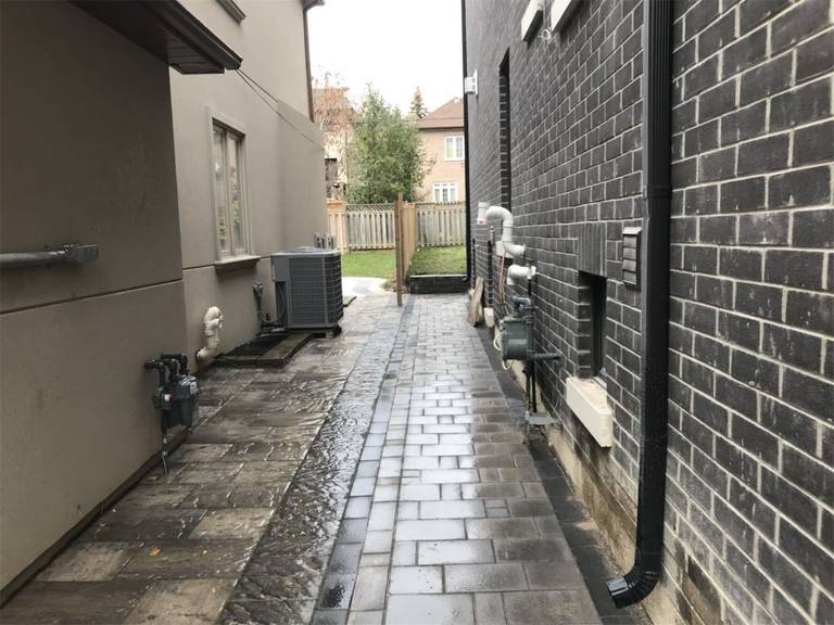 Side yard landscaping project in Toronto featuring a clean interlocking walkway designed for drainage, maintenance access, and improved outdoor functionality. The paved pathway provides durable ground coverage while keeping the side yard organized and accessible.