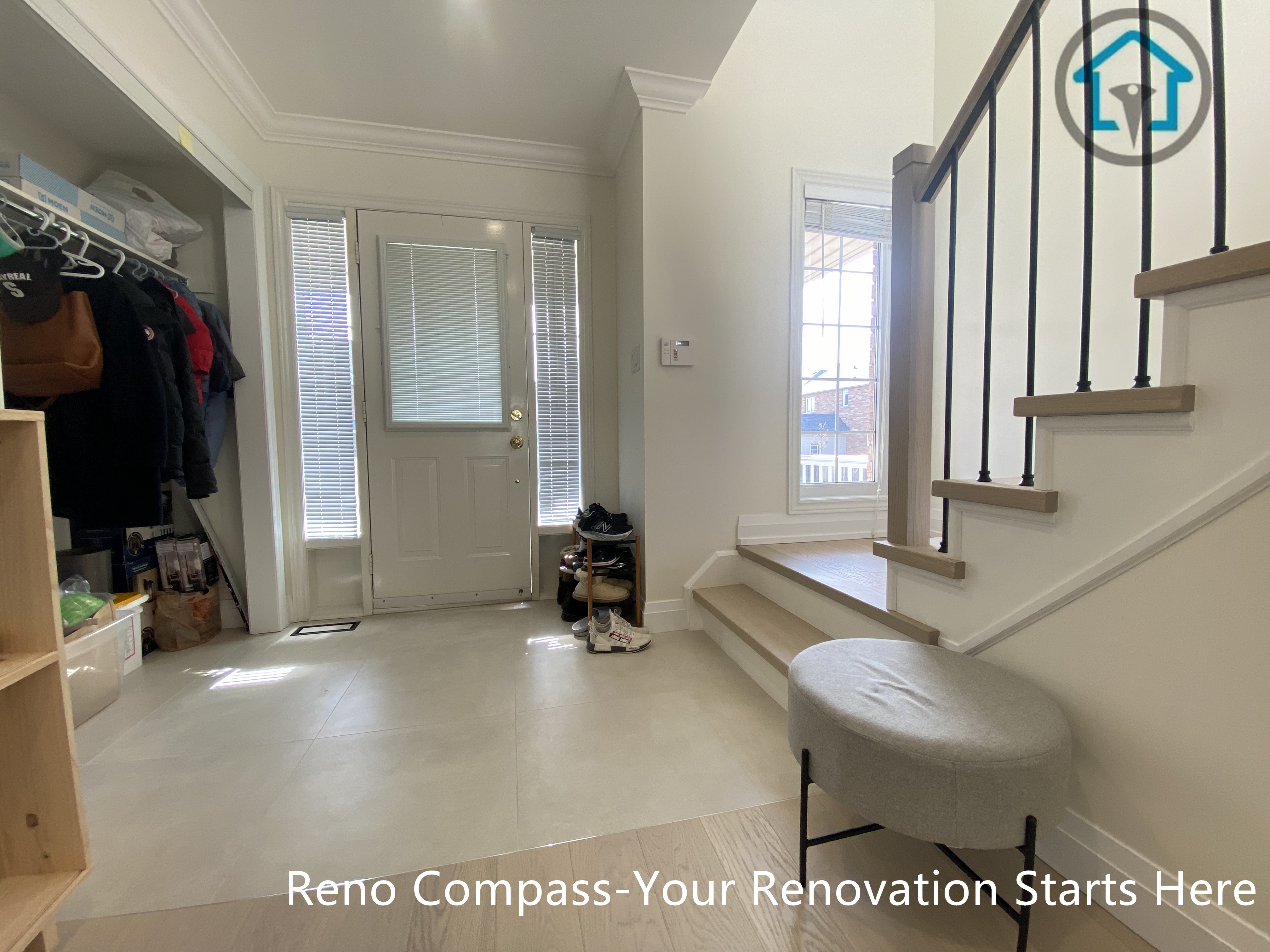 Entryway and staircase renovation in Markham featuring durable light-tone flooring, clean white finishes, and a modern staircase with wood treads and black iron balusters. The flooring transition between the front entrance and stair area improves functionality and visual continuity, creating a welcoming and practical entry space completed by a professional Toronto renovation company.