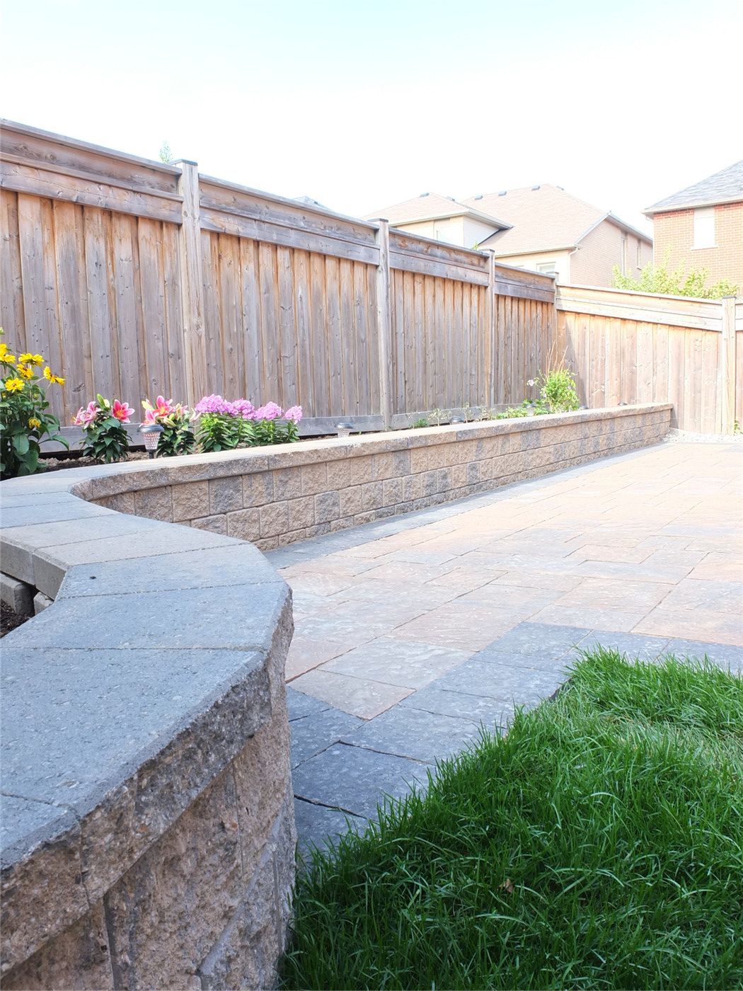 This Toronto backyard landscaping project features a professionally installed interlocking stone patio complemented by a raised retaining wall garden bed and clean lawn transition. The design enhances outdoor functionality while improving drainage, durability, and visual appeal. With precision stonework, structured borders, and low-maintenance landscaping elements, this renovation creates a refined and practical outdoor living space. Completed by an experienced Toronto renovation and landscaping team, the project adds long-term value and modern curb appeal to the property.