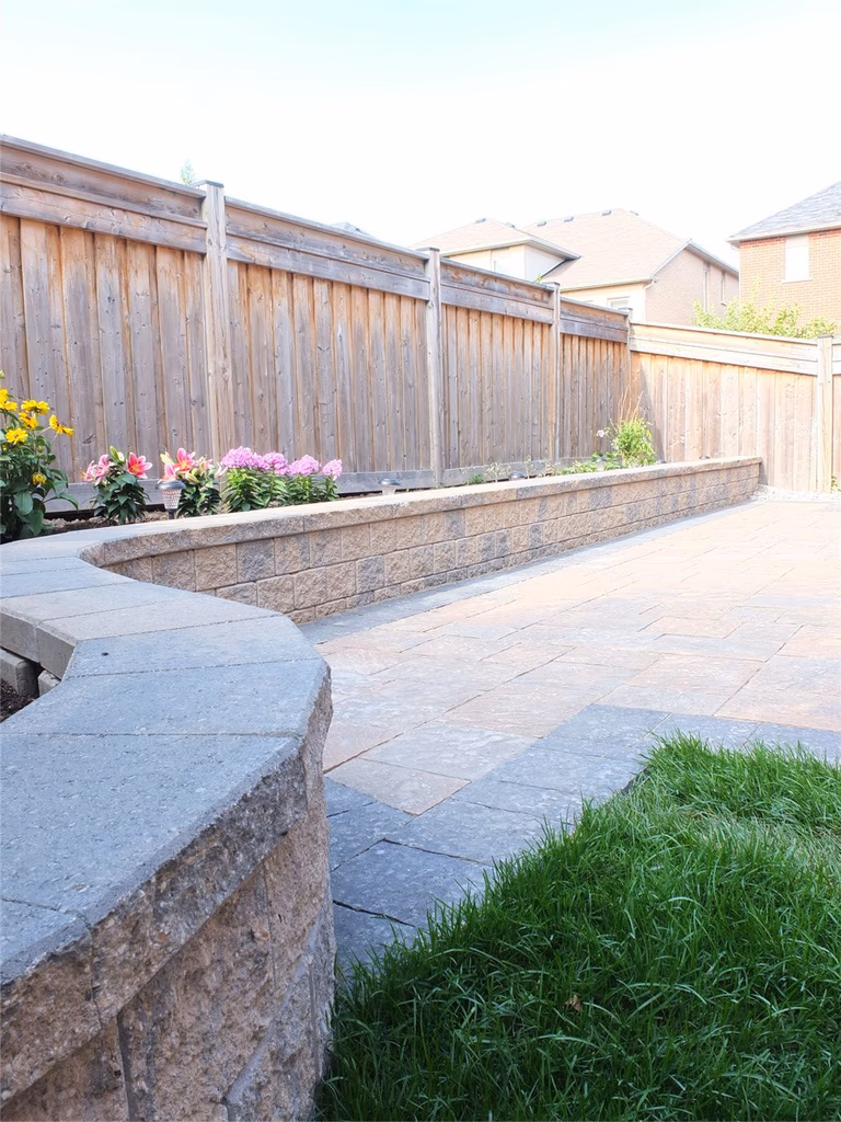 This Toronto backyard landscaping project features a professionally installed interlocking stone patio complemented by a raised retaining wall garden bed and clean lawn transition. The design enhances outdoor functionality while improving drainage, durability, and visual appeal. With precision stonework, structured borders, and low-maintenance landscaping elements, this renovation creates a refined and practical outdoor living space. Completed by an experienced Toronto renovation and landscaping team, the project adds long-term value and modern curb appeal to the property.
