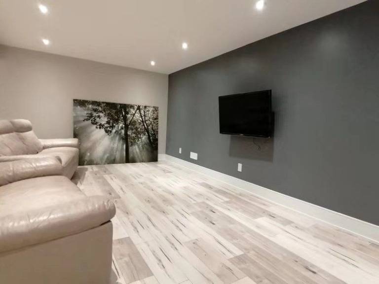 This Richmond Hill interior partial renovation showcases a modern basement living and entertainment space featuring upgraded flooring, recessed lighting, and a contemporary accent wall with mounted TV setup. The redesigned layout creates a comfortable and stylish area for family gatherings, movie nights, and everyday relaxation. Neutral tones and high-quality finishes enhance brightness and visual depth, adding both functionality and value to the home. Completed by Reno Compass, this interior remodeling project highlights professional basement renovation services across Richmond Hill and the Greater Toronto Area.