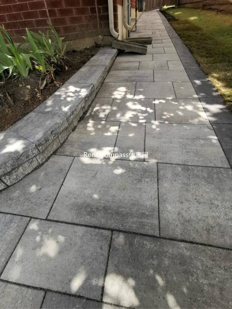 Beautifully finished side walkway interlocking project in Richmond Hill. The light gray stone pavers are neatly aligned against the house, featuring a raised garden border for a clean and modern look. Installed by Reno Compass for improved drainage, durability, and curb appeal.