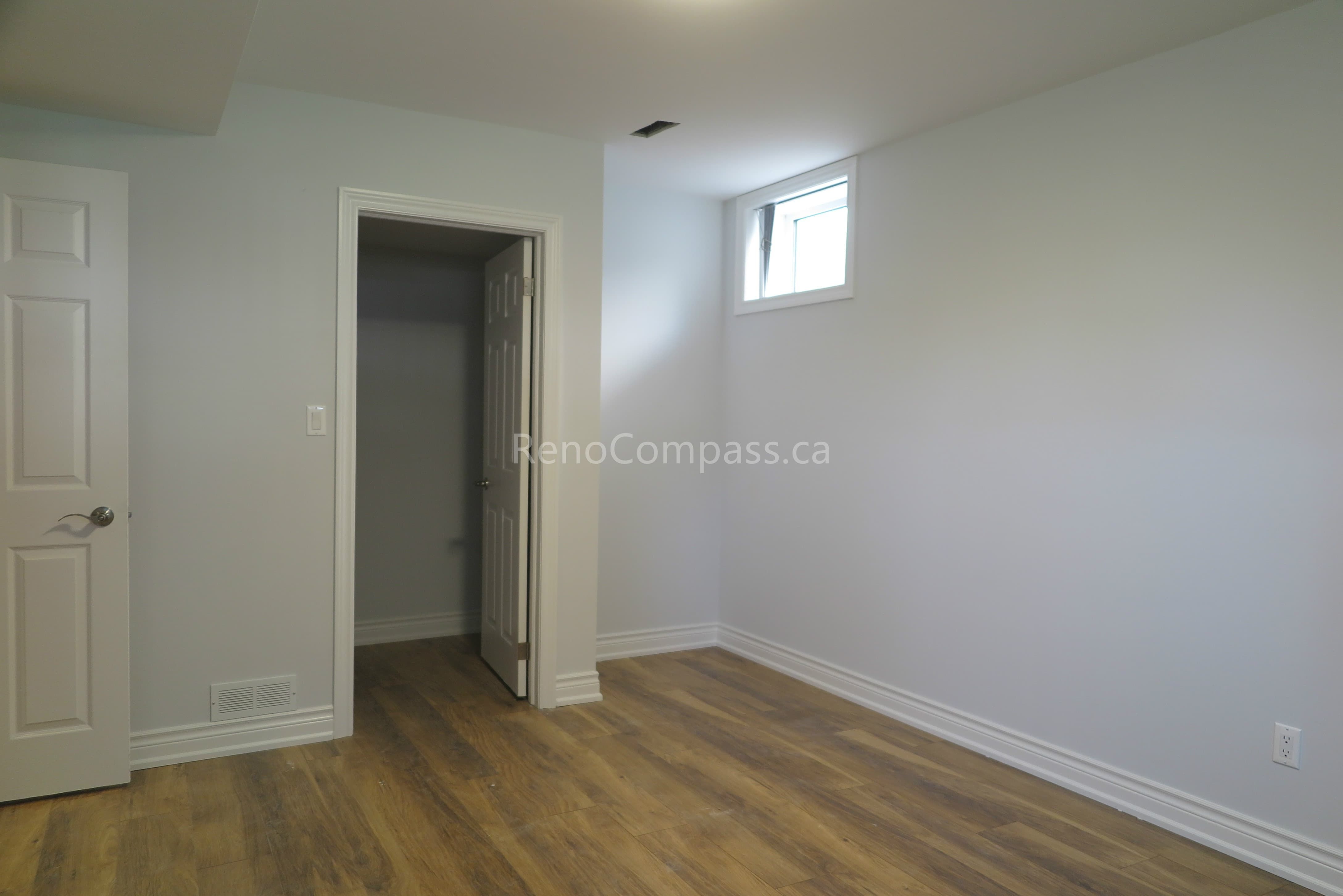 This North York interior renovation features a newly finished basement bedroom with modern hardwood flooring, clean white walls, and upgraded trim detailing. The redesigned layout improves brightness and functionality with a properly positioned window and smooth wall finishing. Completed by a reliable Toronto renovation company, Reno Compass delivers practical space planning and quality craftsmanship to transform basement areas into comfortable, livable rooms.