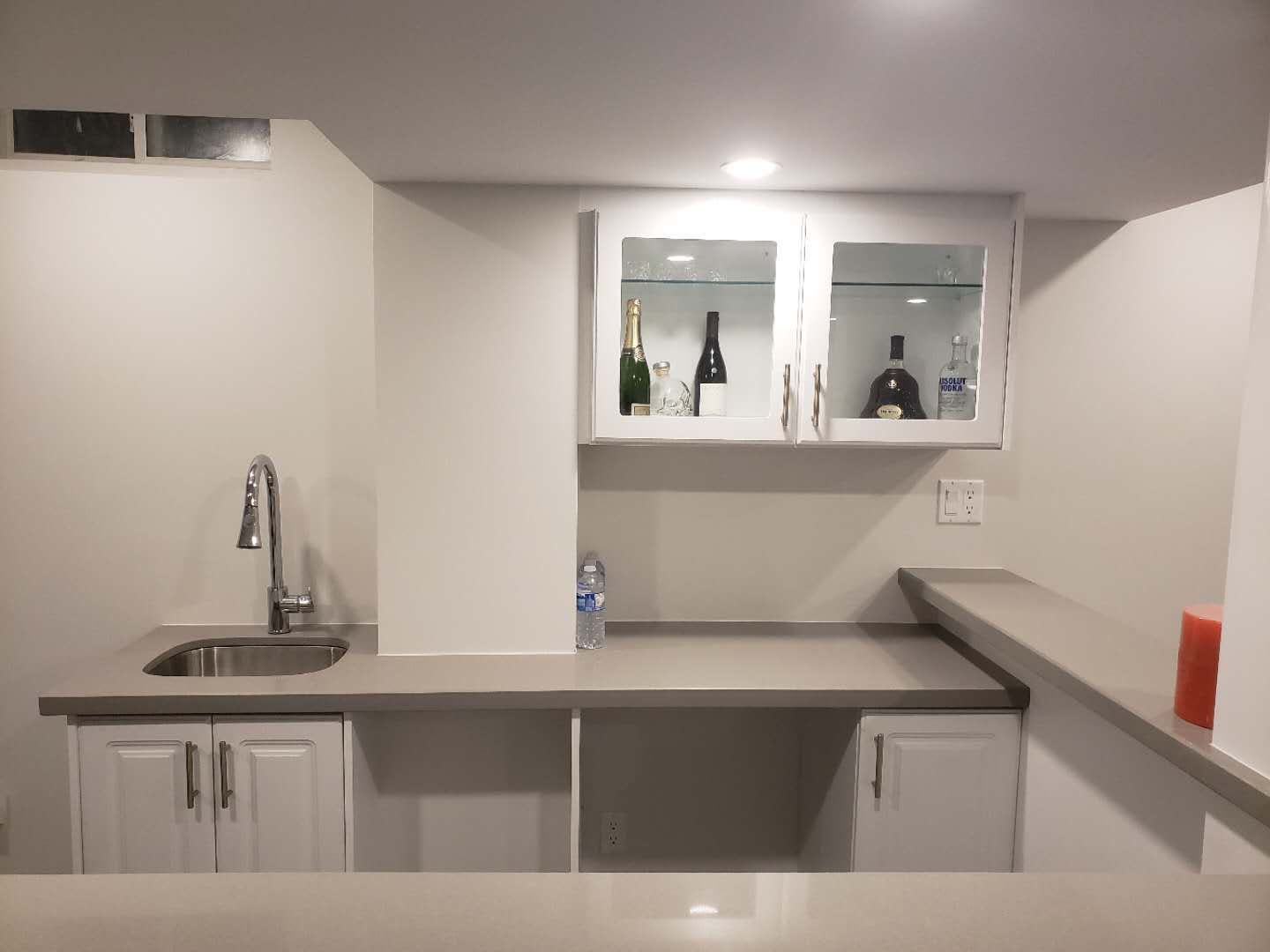 This Markham basement renovation features a clean and modern bar area with custom white cabinetry, a built-in sink, and a functional island countertop. Recessed pot lights and smooth ceiling finishes enhance brightness, while dark flooring adds contrast and warmth. The layout is designed to maximize usability and flow, making the basement ideal for entertaining, family gatherings, or multi-purpose living. This project reflects professional basement renovation standards in Markham, focusing on durability, lighting, and practical space planning.