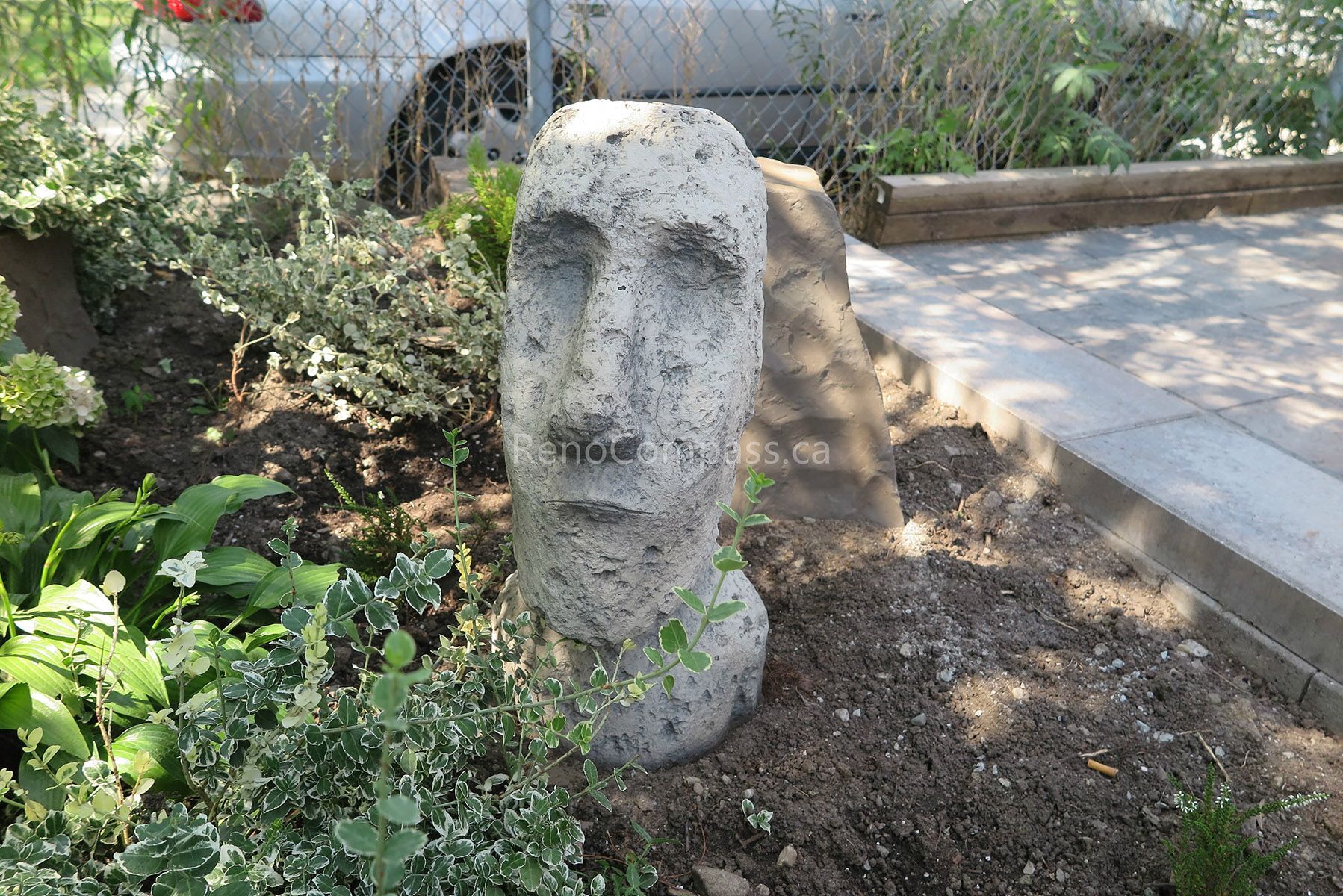 This Mississauga landscaping renovation features a thoughtfully designed garden bed with natural stone decorative elements and layered planting. The custom landscape layout integrates ornamental stone features, fresh soil preparation, and structured edging to create visual interest and depth. Combined with new interlocking surfaces and surrounding greenery, the space delivers a balanced and welcoming outdoor environment. Completed by Reno Compass Inc., this project reflects creative landscape design and professional installation.
