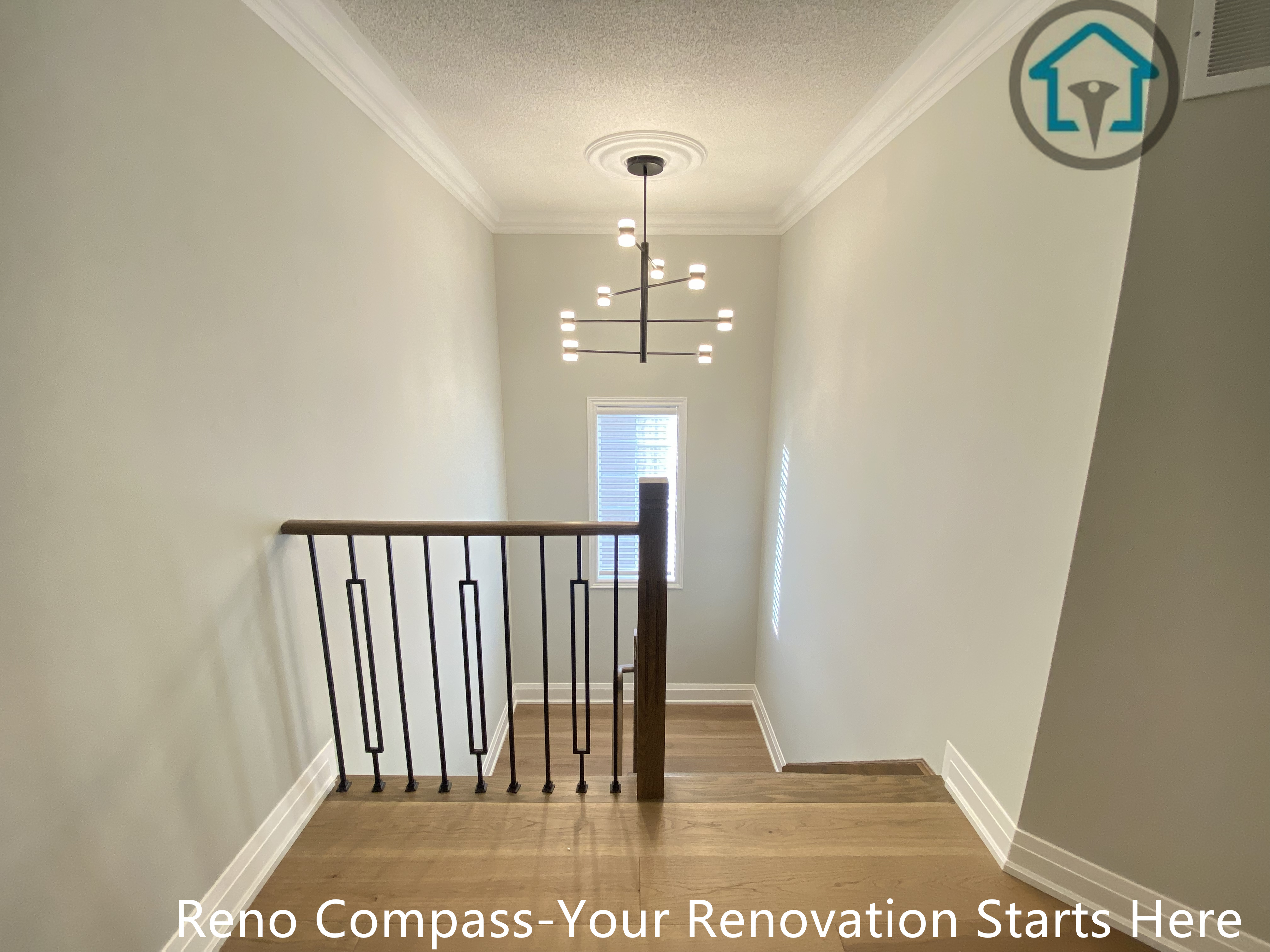 This image shows the upper hallway and stair landing area of a flooring and staircase renovation project in Richmond Hill. The space features continuous hardwood flooring, clean wall finishes, and modern black iron railings that create a safe yet visually open transition between rooms and levels. Natural light from multiple windows enhances the brightness and depth of the hallway. Completed by a reliable Toronto renovation company, the renovation emphasizes smooth circulation, durable materials, and a cohesive modern interior design.