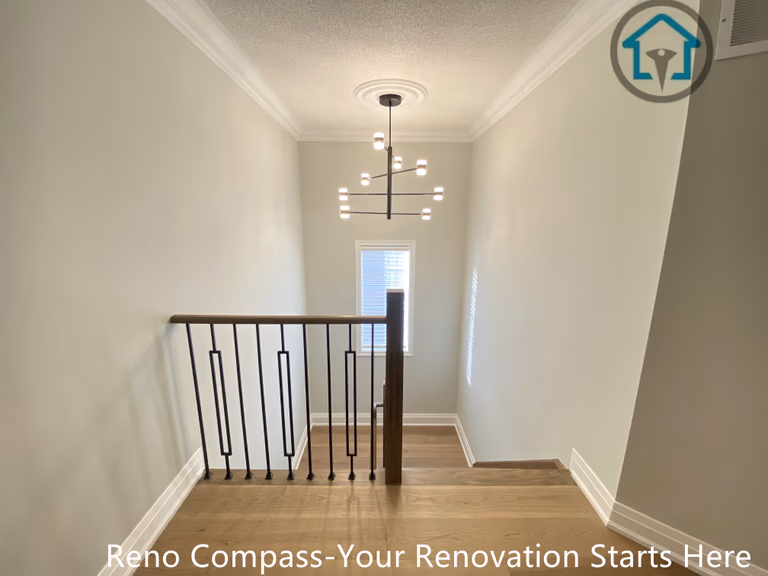 This image shows the upper hallway and stair landing area of a flooring and staircase renovation project in Richmond Hill. The space features continuous hardwood flooring, clean wall finishes, and modern black iron railings that create a safe yet visually open transition between rooms and levels. Natural light from multiple windows enhances the brightness and depth of the hallway. Completed by a reliable Toronto renovation company, the renovation emphasizes smooth circulation, durable materials, and a cohesive modern interior design.