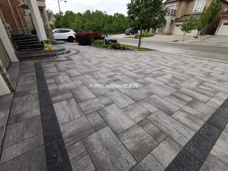Close-up view of a professionally installed interlocking stone driveway in Vaughan, showcasing high-quality grey pavers, precise alignment, and seamless integration with the front steps and garden edge. RenoCompass delivers premium craftsmanship built to last.