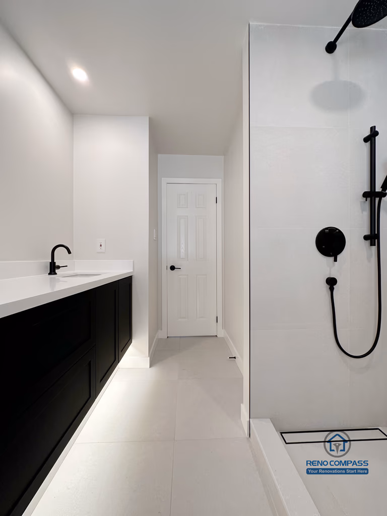 Modern bathroom renovation in Markham featuring a glass walk-in shower, matte black fixtures, and a sleek vanity with ample storage. The linear layout, bright finishes, and minimalist detailing create a clean, functional bathroom designed for everyday comfort and easy maintenance.