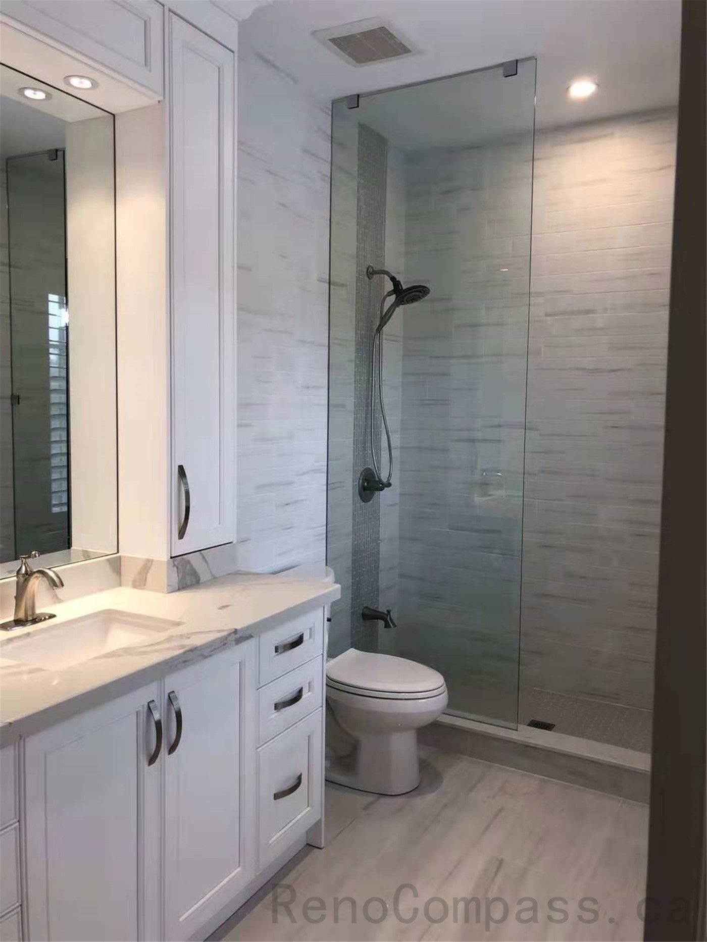 This North York bathroom renovation features a modern glass walk-in shower with marble-look wall tiles, a custom vanity with quartz countertop, and bright integrated lighting. The clean layout and contemporary finishes create a functional and elegant space designed for everyday comfort. Completed by a professional Toronto renovation company specializing in high-quality residential bathroom renovations.