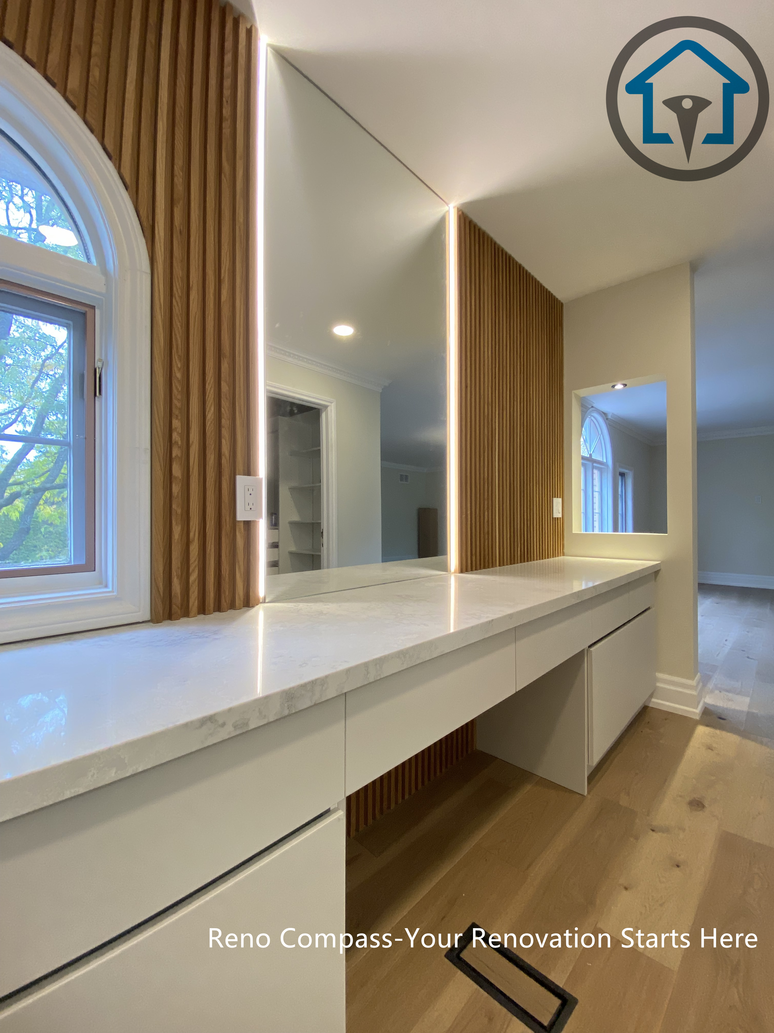 This custom bathroom vanity features clean-lined cabinetry, integrated LED mirror lighting, and warm wood panel accents, creating a balanced blend of functionality and modern design.
