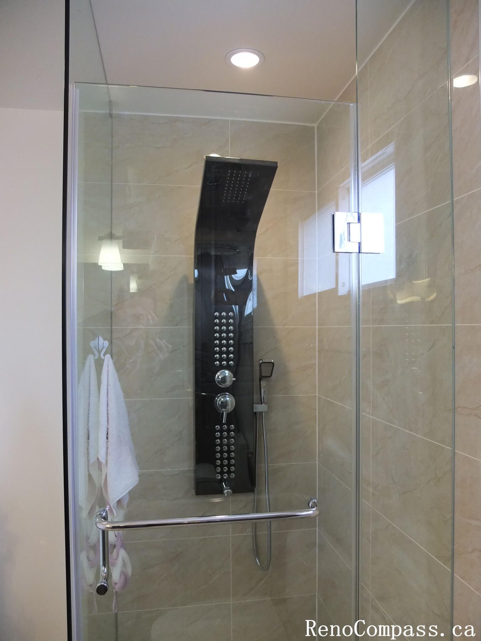 Interior bathroom renovation in North York featuring a frameless glass shower, full-body rain shower system, and large-format porcelain wall tiles. This Toronto interior renovation focuses on modern functionality, clean detailing, and efficient use of space for everyday comfort.