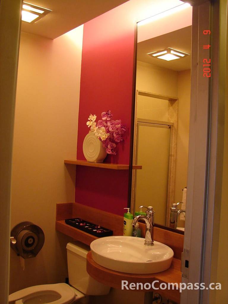 This Toronto beauty salon commercial renovation includes a stylish and functional washroom design featuring a modern vessel sink, custom vanity, and bold accent wall. Warm lighting and clean finishes create a welcoming, boutique-style restroom that complements the overall salon interior. Designed for both aesthetics and durability, this commercial bathroom renovation reflects professional craftsmanship and thoughtful planning by a trusted Toronto renovation company.