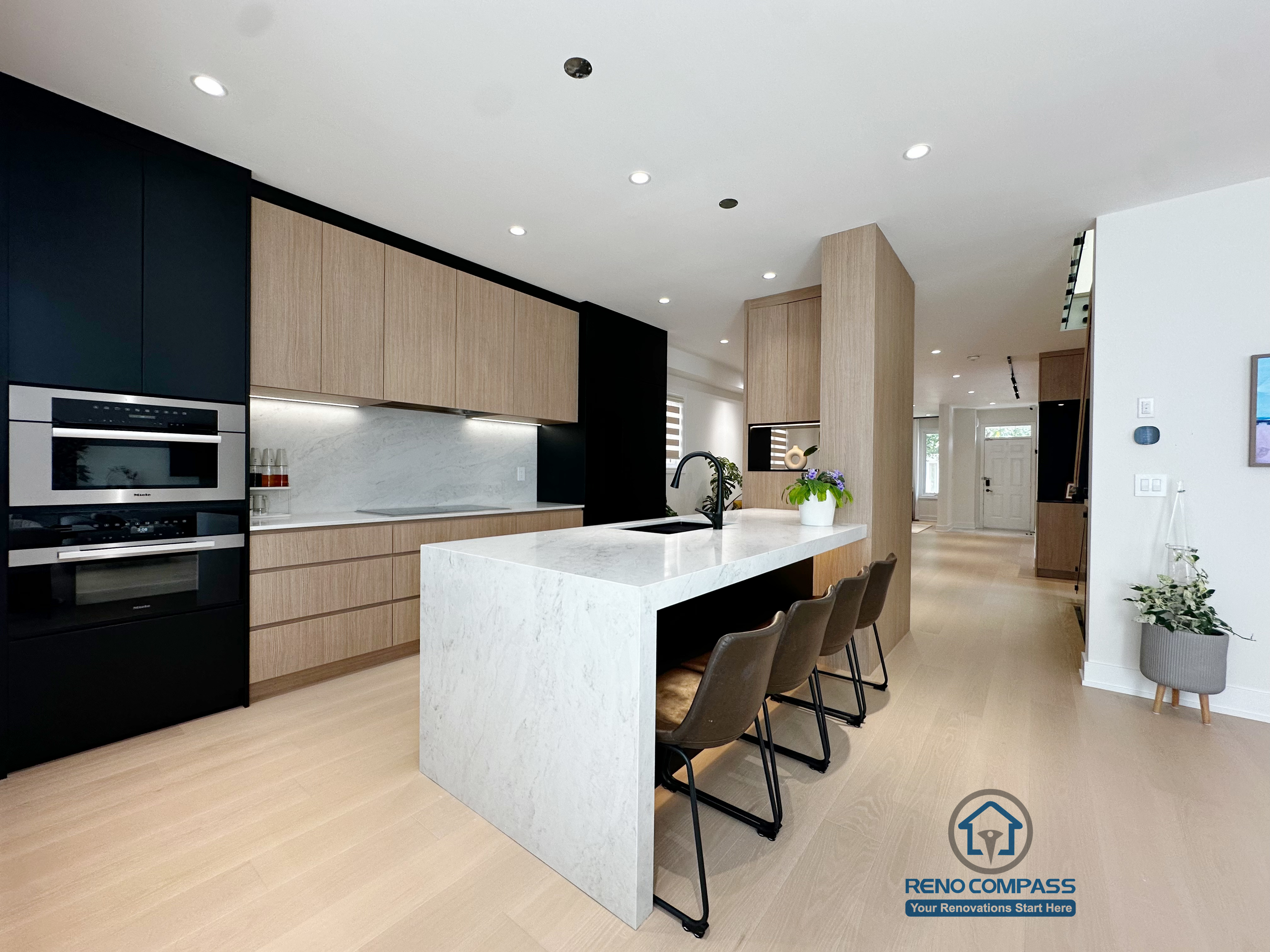 This modern kitchen renovation in Markham features a waterfall-edge central island, integrated built-in appliances, and custom wood cabinetry. Designed and constructed by Reno Compass, the open-concept layout enhances natural flow, functionality, and a refined contemporary aesthetic.