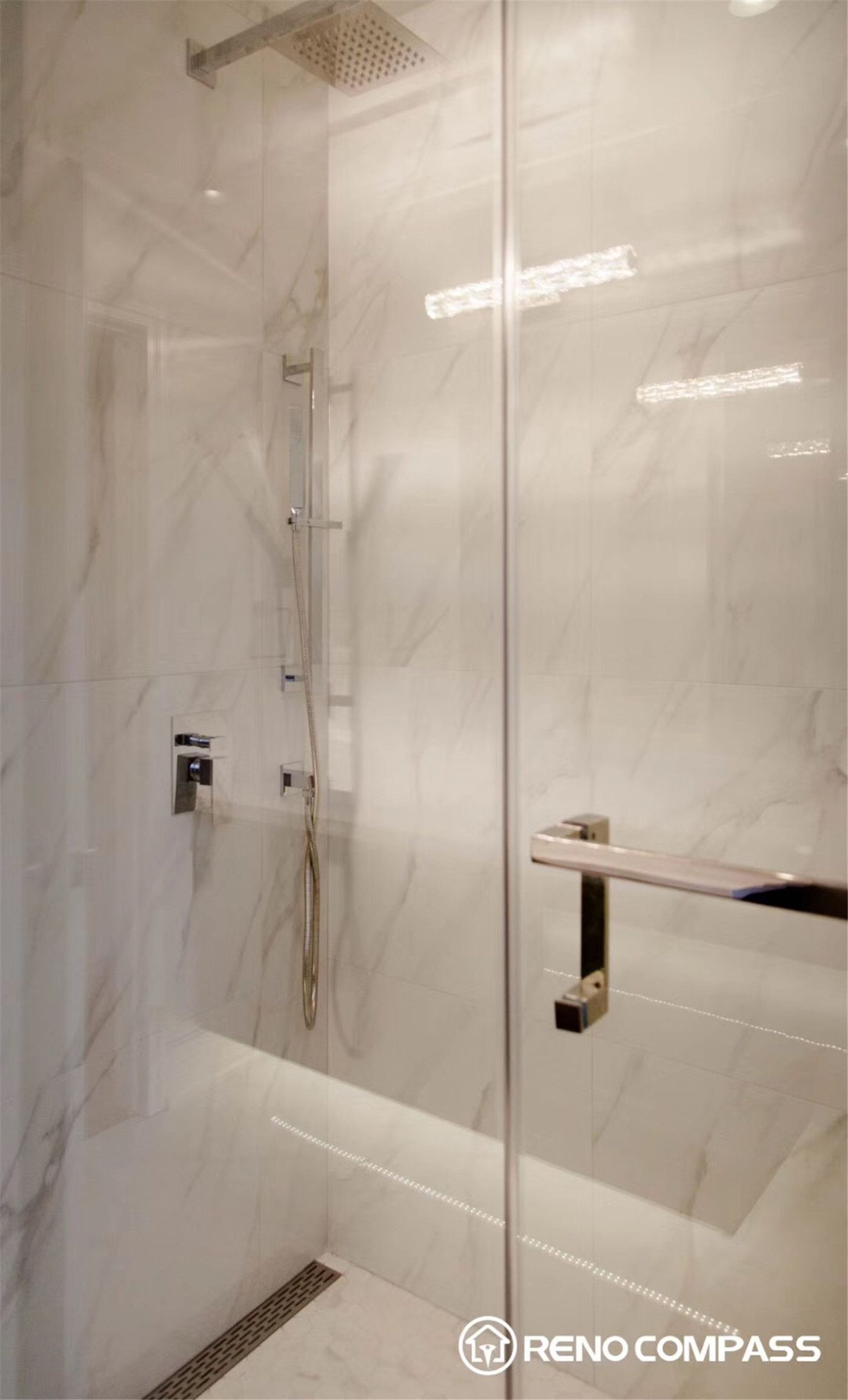 This Markham bathroom renovation features a sleek walk-in glass shower with large-format marble-look tiles and a minimalist design. The space is completed with modern fixtures, a rainfall shower head, and a linear drain, creating a clean, spa-like atmosphere with both functionality and elegance.