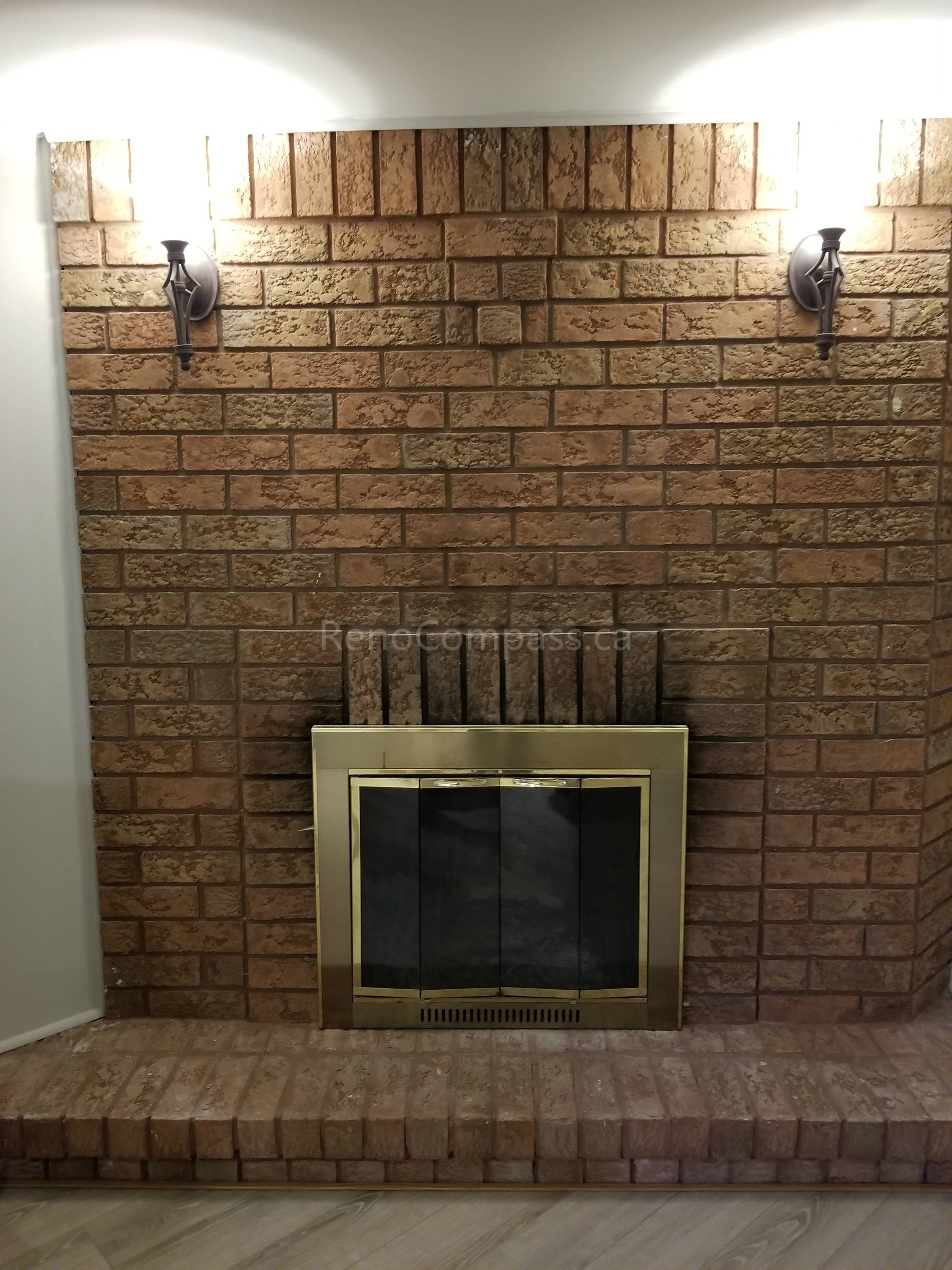 This Toronto basement renovation highlights a classic brick fireplace feature wall with updated lighting and refreshed flooring. The warm-toned brick surround and modern wall sconces create a cozy focal point, enhancing the comfort and character of the basement living space. Completed by Reno Compass Inc., this fireplace upgrade adds charm, functionality, and visual appeal to the finished basement interior.