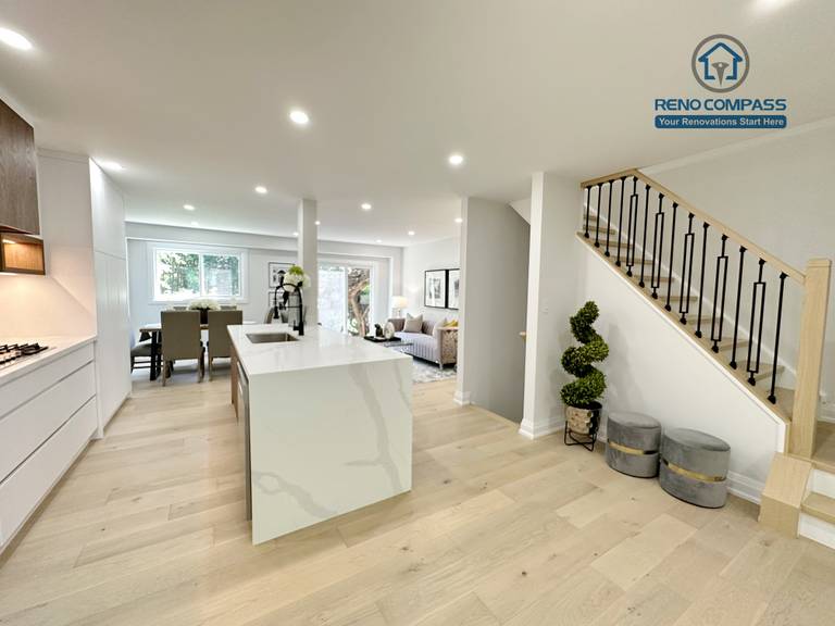 This Richmond Hill interior renovation features a bright open-concept kitchen and living space with custom white cabinetry, integrated stainless steel appliances, a waterfall kitchen island, and wide-plank hardwood flooring. Designed and completed by a Toronto renovation company, the layout enhances natural light, functionality, and modern living comfort for contemporary family homes.
