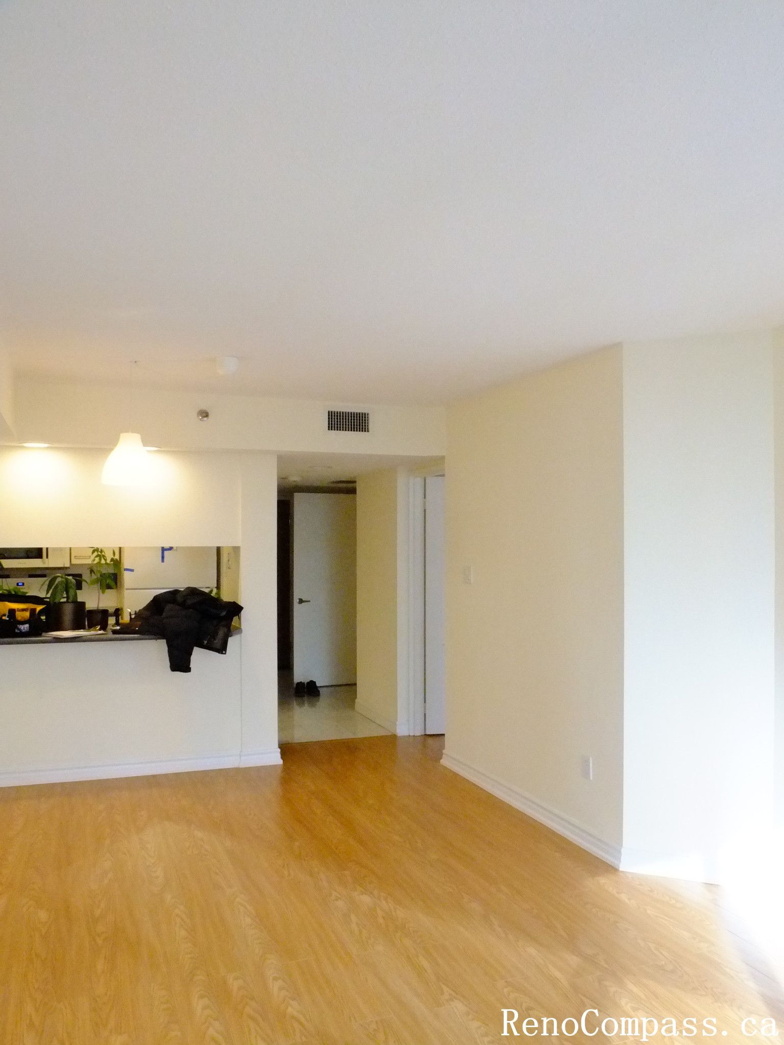 Completed Toronto condo interior renovation showcasing new flooring, a bright open living room, and a functional kitchen layout. This renovation enhances the overall space with improved lighting, clean finishes, and a modern open-concept design.