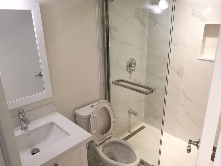 Scarborough whole-house interior renovation featuring a fully upgraded bathroom with glass shower enclosure, modern vanity, and marble-style wall tiles. This renovation highlights improved functionality, clean finishes, and a bright contemporary design completed by a professional Toronto renovation contractor.