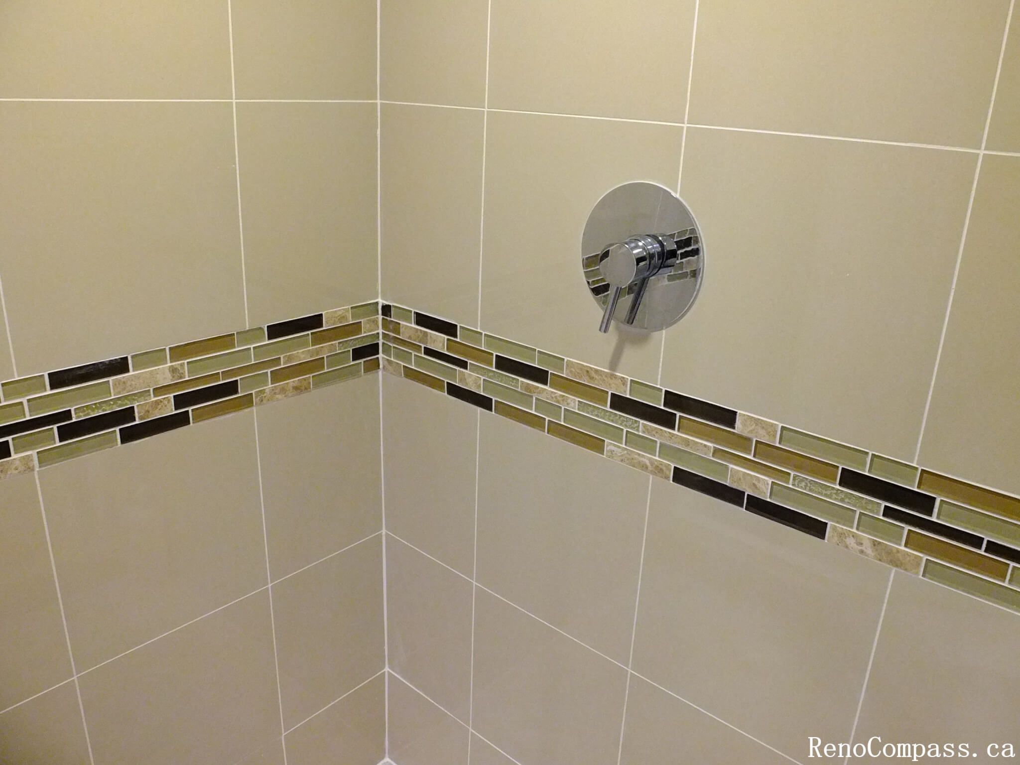 This Mississauga bathroom renovation highlights a clean and modern shower wall design featuring large-format beige tiles paired with a decorative mosaic accent strip. The horizontal mosaic band adds visual interest and depth while maintaining a balanced, neutral color palette. The chrome shower control fixture complements the tile work and provides a sleek, contemporary finish. This detail-focused installation demonstrates quality craftsmanship and thoughtful design, enhancing both the style and durability of the bathroom space.