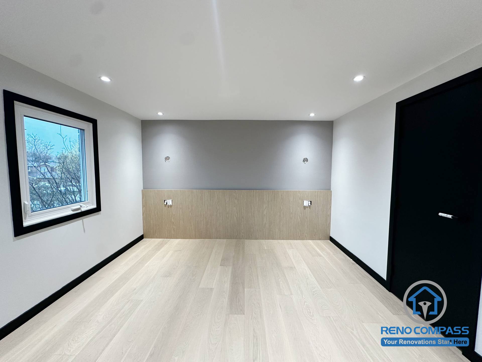 This bedroom in Richmond Hill features a clean modern upgrade with a soft grey accent wall and custom wood paneling. The minimalist design improves warmth, storage possibilities, and overall comfort. A bright window and balanced lighting further enhance the peaceful atmosphere. 这间位于列治文山的卧室经过现代化升级，以柔和的灰色特色墙搭配温润的木纹护墙板，让空间更显温暖与质感。极简设计提升了整体舒适度，明亮窗户与均匀灯光营造出宁静、放松的休息氛围。