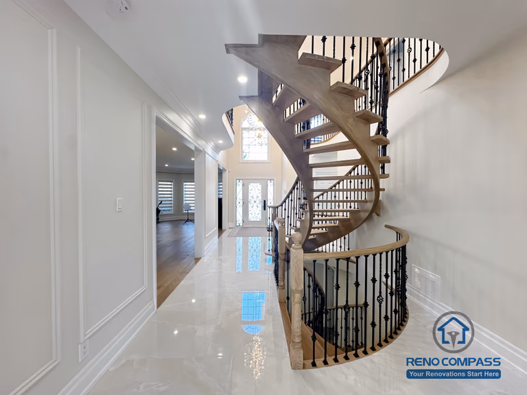 This image highlights a custom curved staircase featured in a North York flooring and stair renovation. The open-riser staircase is constructed with hardwood treads and paired with decorative iron railings, creating a visually light and sculptural form. The surrounding flooring and polished finishes enhance brightness and spatial flow throughout the main level. This design demonstrates precise craftsmanship and thoughtful integration of flooring and stair elements, contributing to a refined and cohesive interior layout for North York homes.