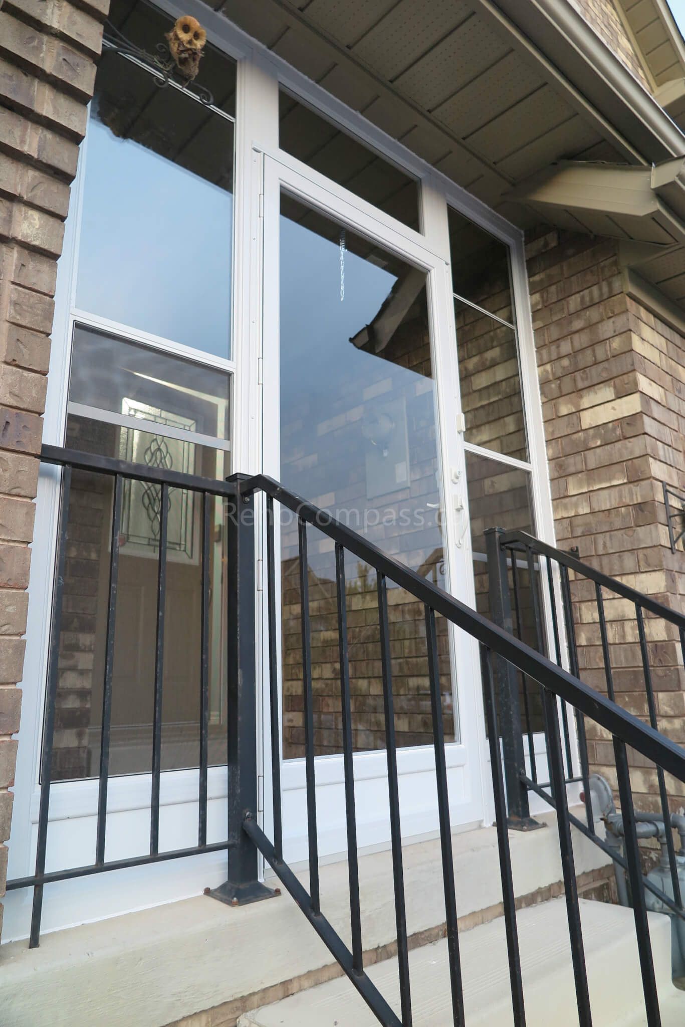 After photo of a Markham home storm door installation project by  Reno Compass Inc. Featuring a modern aluminum-framed storm door with clear glass panels and black railing, this upgrade improves both safety and energy efficiency while keeping the exterior stylish and durable.