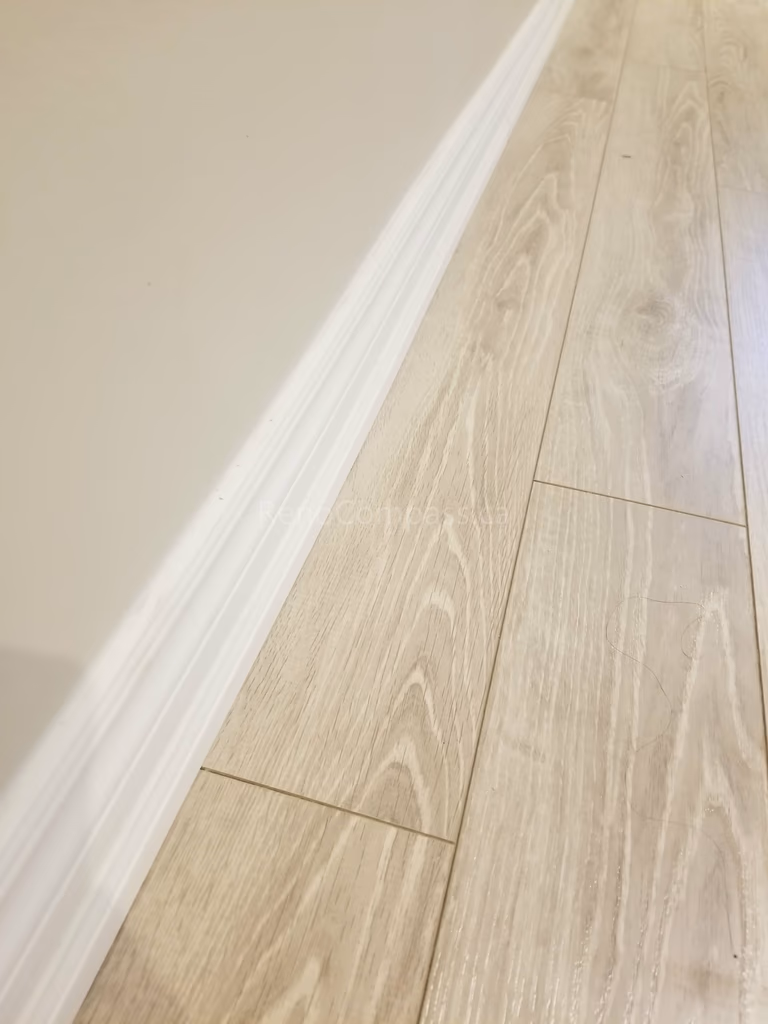 This Toronto basement renovation showcases newly installed light wood flooring paired with clean white baseboards for a modern and elegant finish. The durable laminate flooring enhances brightness and creates a warm, contemporary look while providing easy maintenance for basement living spaces. Installed by Reno Compass Inc., this flooring upgrade adds both style and functionality to the newly renovated basement interior.