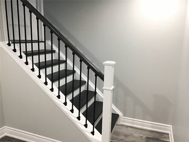 Basement staircase renovation in Newmarket featuring dark stained wood treads, white risers, and sleek black metal railings. This stylish stair upgrade seamlessly connects the main floor to the newly finished basement while enhancing safety and visual appeal.