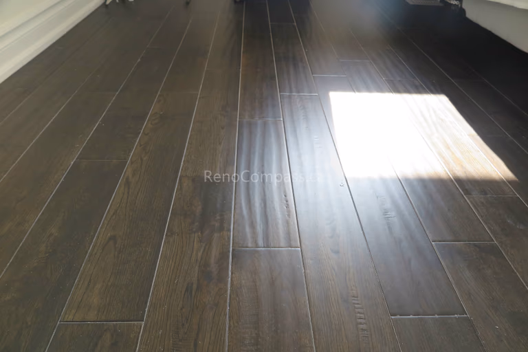 This image shows a completed North York flooring renovation with dark hardwood flooring illuminated by natural daylight. The even plank alignment and smooth surface reflect light beautifully, enhancing the depth and warmth of the space. As a trusted Toronto Renovation Company, Reno Compass Inc. delivers high-quality flooring installations that perform well under daily use while maintaining a refined and welcoming residential atmosphere.
