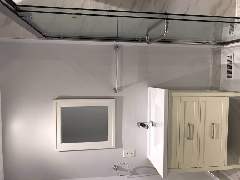 Modern Toronto bathroom renovation featuring a custom vanity cabinet, wall-mounted mirror, chrome fixtures, and glossy marble wall tiles styled for a bright and elegant finish.