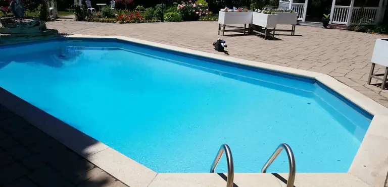 After renovation photo of a fully restored backyard swimming pool in Toronto. The new bright blue liner, clean water, and resurfaced edges highlight the professional pool transformation from old and damaged to modern and inviting. Expert pool renovation by local Toronto specialists.