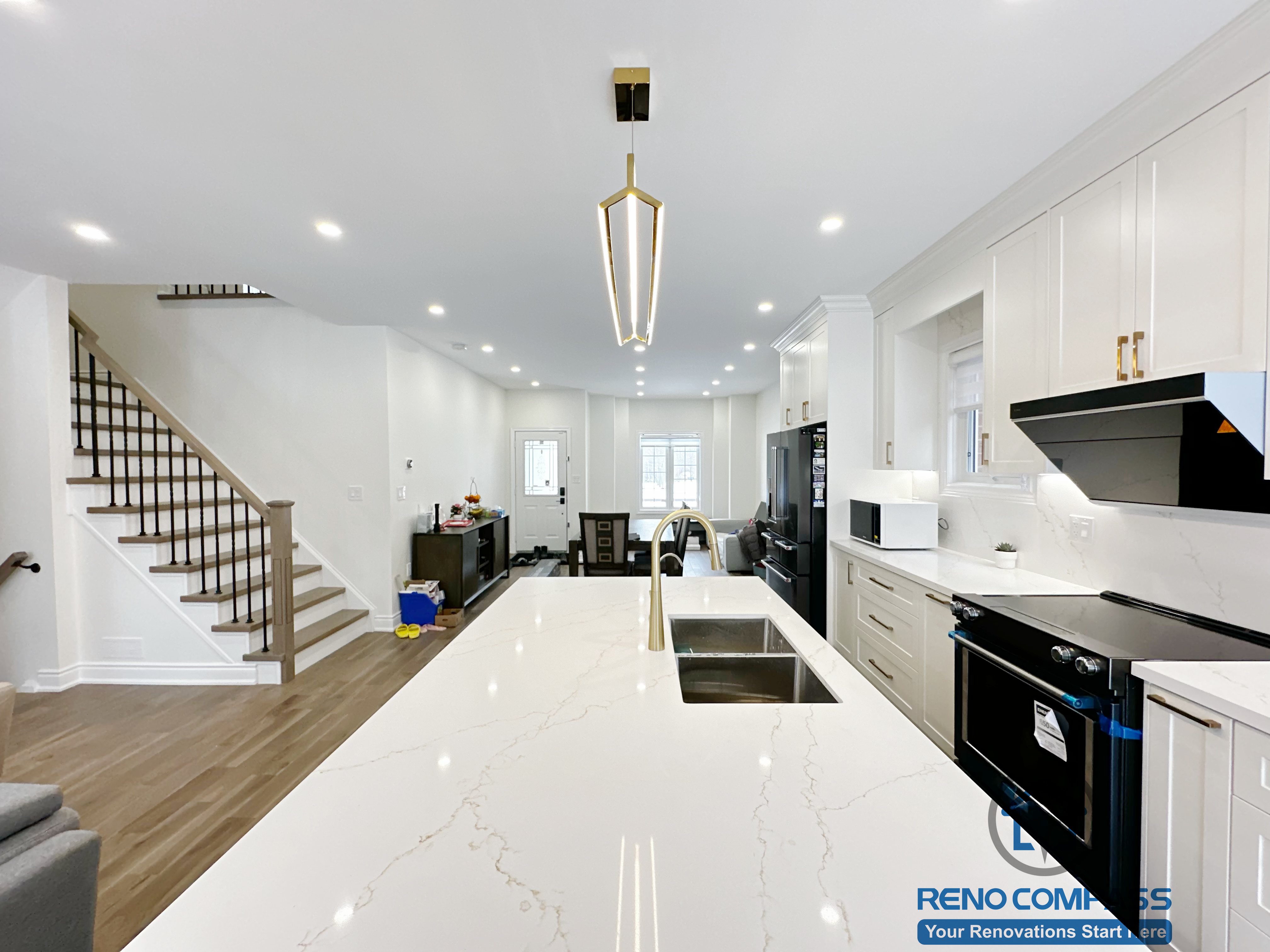 Interior renovation in Markham highlighting a spacious kitchen island with quartz countertop, integrated sink, and modern pendant lighting. The design enhances workflow, visual openness, and seamless connection between the kitchen and surrounding living areas.