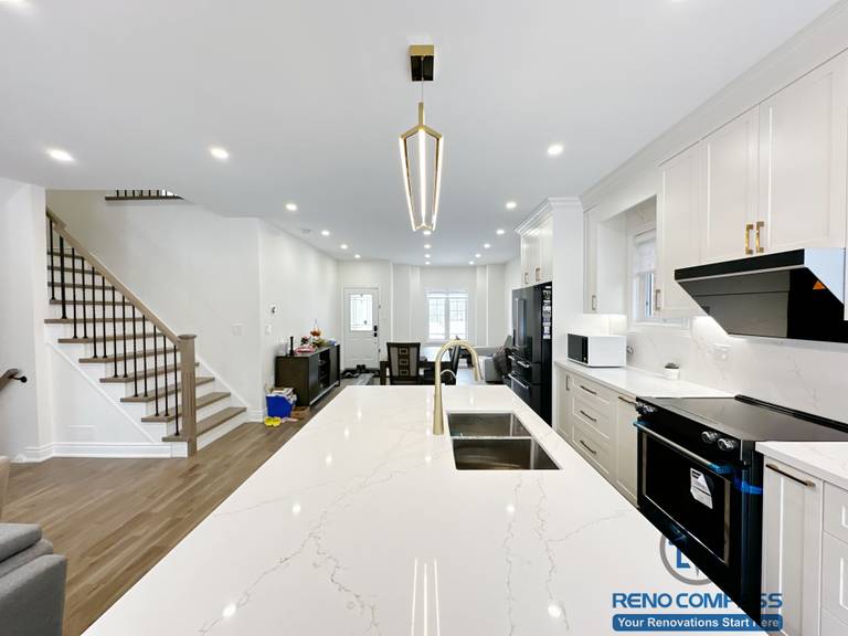 Interior renovation in Markham highlighting a spacious kitchen island with quartz countertop, integrated sink, and modern pendant lighting. The design enhances workflow, visual openness, and seamless connection between the kitchen and surrounding living areas.