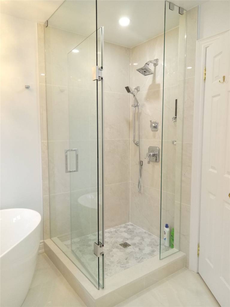 This bathroom renovation in Richmond Hill features a frameless glass corner shower with a clean tile finish, modern rainfall shower system, and a slip-resistant mosaic shower base. The transparent glass enclosure enhances spatial openness while maintaining a sleek, modern appearance. As part of a full interior renovation, this shower installation reflects precise craftsmanship, proper waterproofing, and durable material selection completed by a professional Toronto renovation company serving Richmond Hill homeowners.