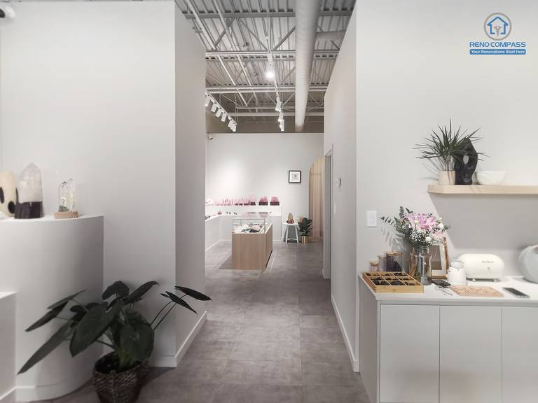 This image provides a full interior overview of a crystal shop renovation in Markham, showcasing the main entrance perspective and overall store layout. Clear sightlines, polished concrete flooring, custom display islands, and wall-mounted shelving guide customer flow naturally through the space. Neutral finishes and balanced lighting create a calm, inviting retail environment. As a Toronto renovation company, Reno Compass specializes in thoughtfully planned retail renovations that enhance both functionality and customer experience.