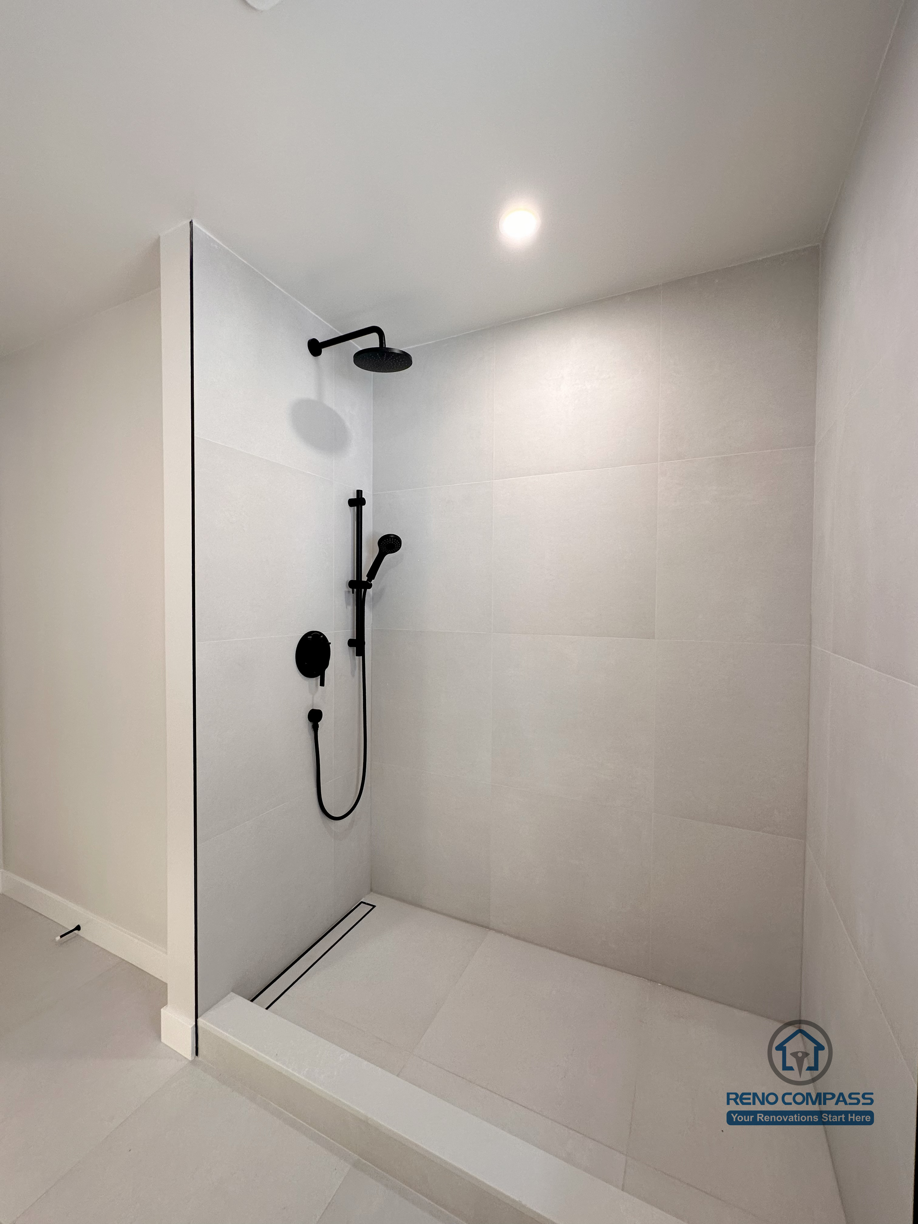 Modern bathroom renovation in Markham featuring a curbless walk-in shower with matte black fixtures and large-format wall tiles. The minimalist design improves accessibility, simplifies maintenance, and creates a clean, contemporary shower space ideal for daily use.