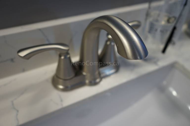Close-up of a modern brushed nickel bathroom faucet installed on a marble countertop as part of a Markham bathroom renovation. The upgraded sink fixtures combine durability, functionality, and elegant design, adding a refined finishing touch to this clean and contemporary bathroom space.